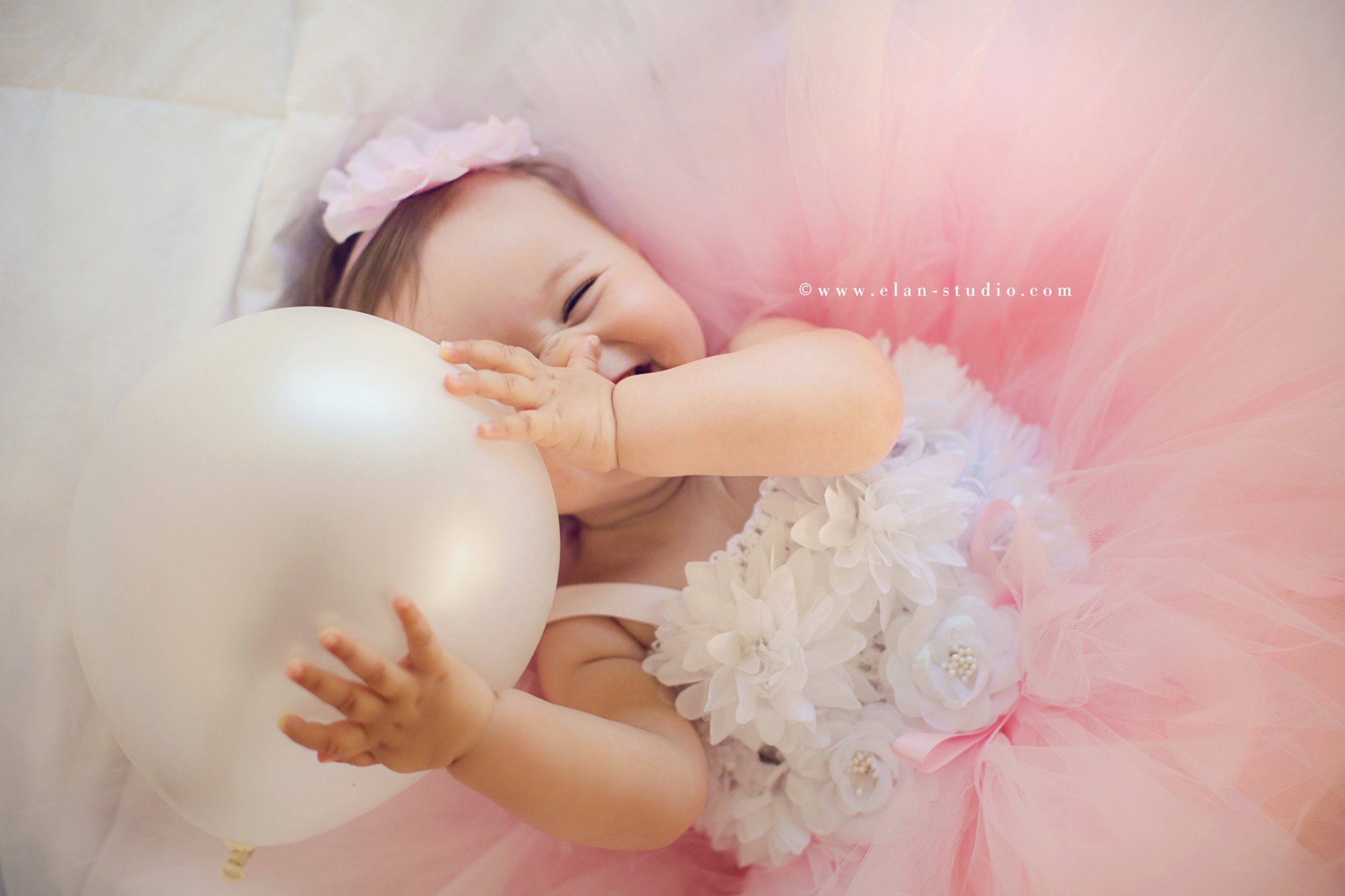 laughing baby girl with pink balloon