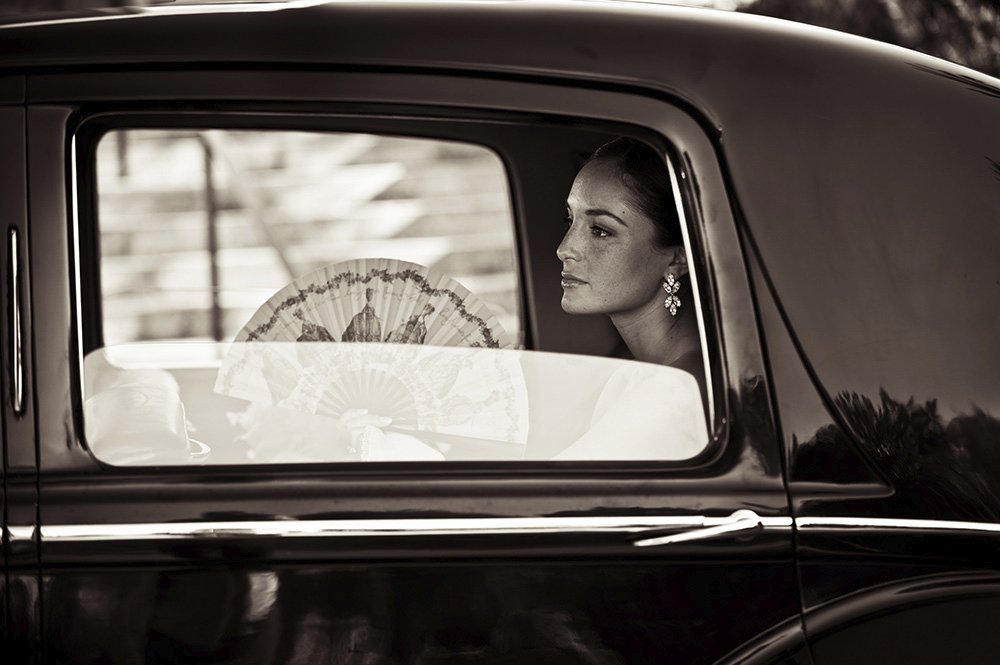 Bride with fan and earrings in vintage car