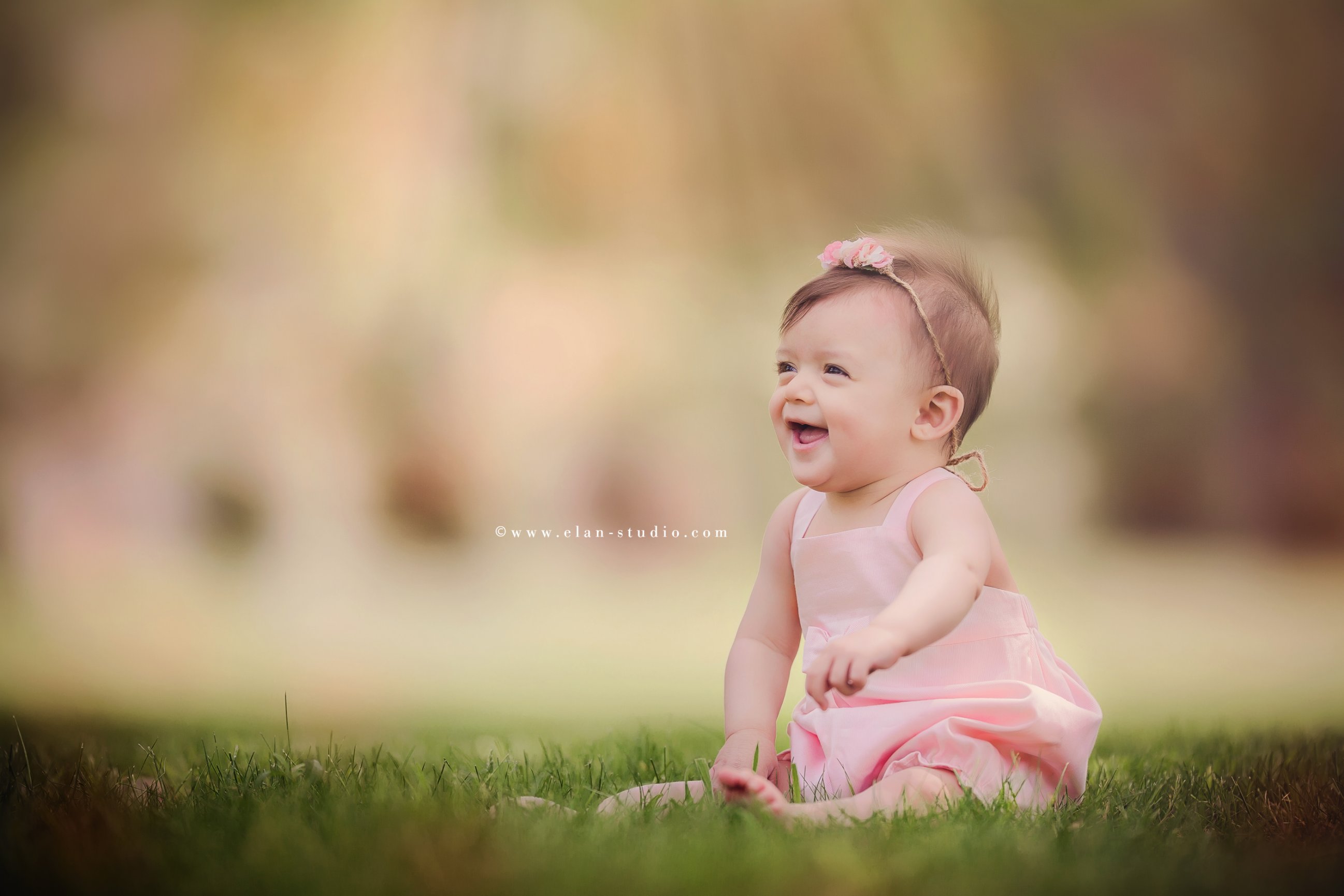 smiling sitting baby girl with a pink romper, green grass, background bokeh, Tracy Sweeney