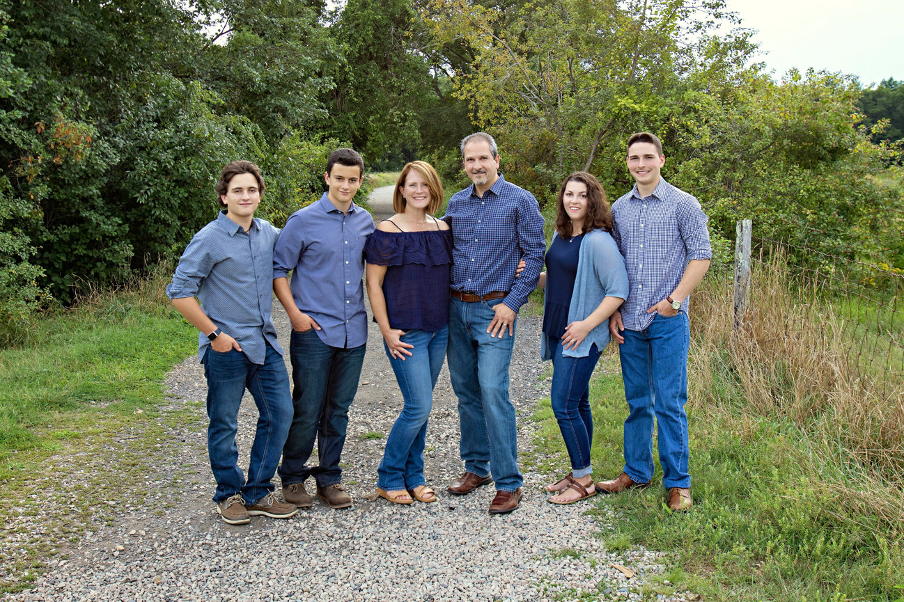 Outdoor family portrait of four young adult children and parents on dirt pathway in blue color palette Rhode Island