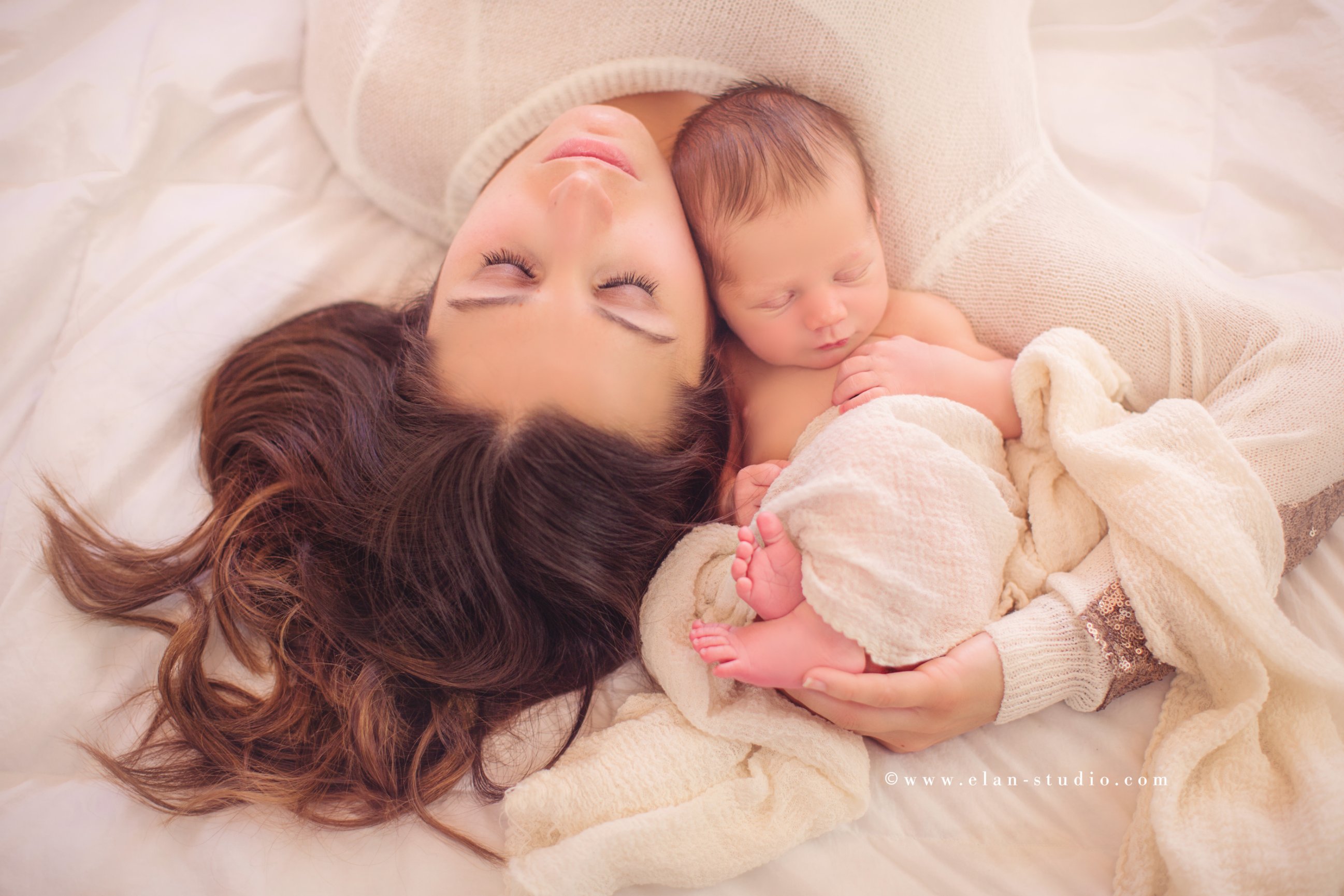 mother cradling newborn baby on a bed, creamy motherhood portrait edit, Elan Studio