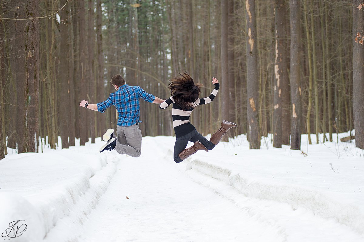 fun photo of engaged couple jumping in snow