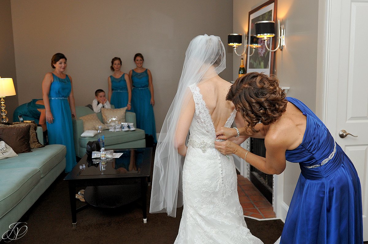 bride getting dress help from mother