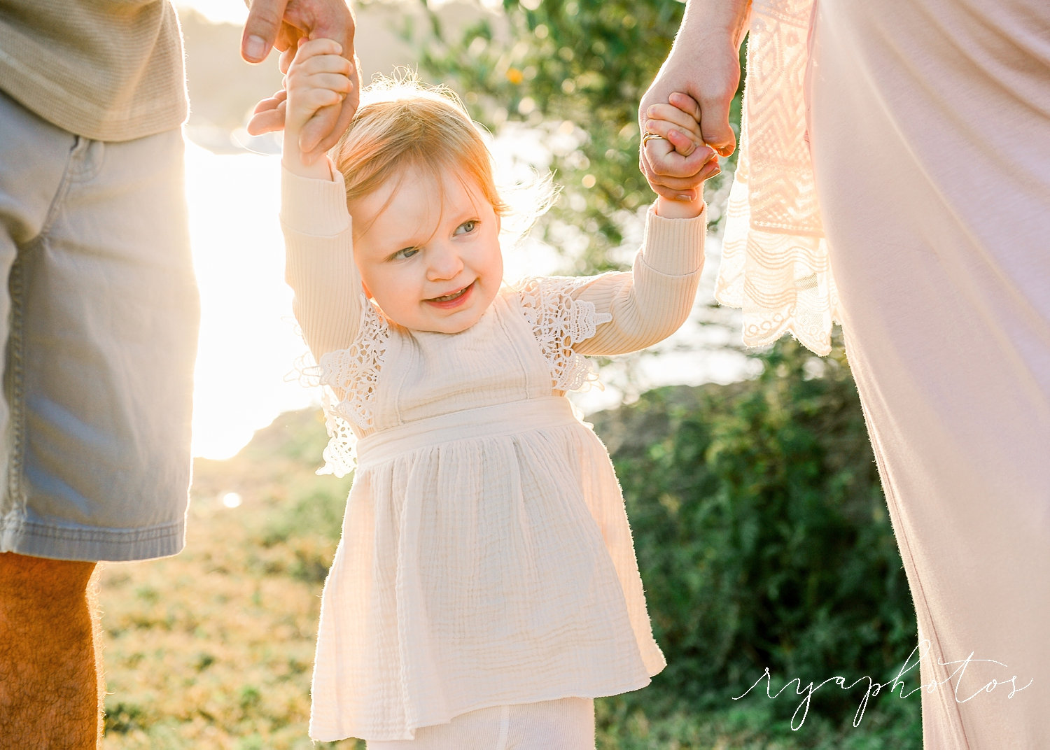 smiling toddler holding mom and dad's hands, bohemian family maternity session, Ryaphotos