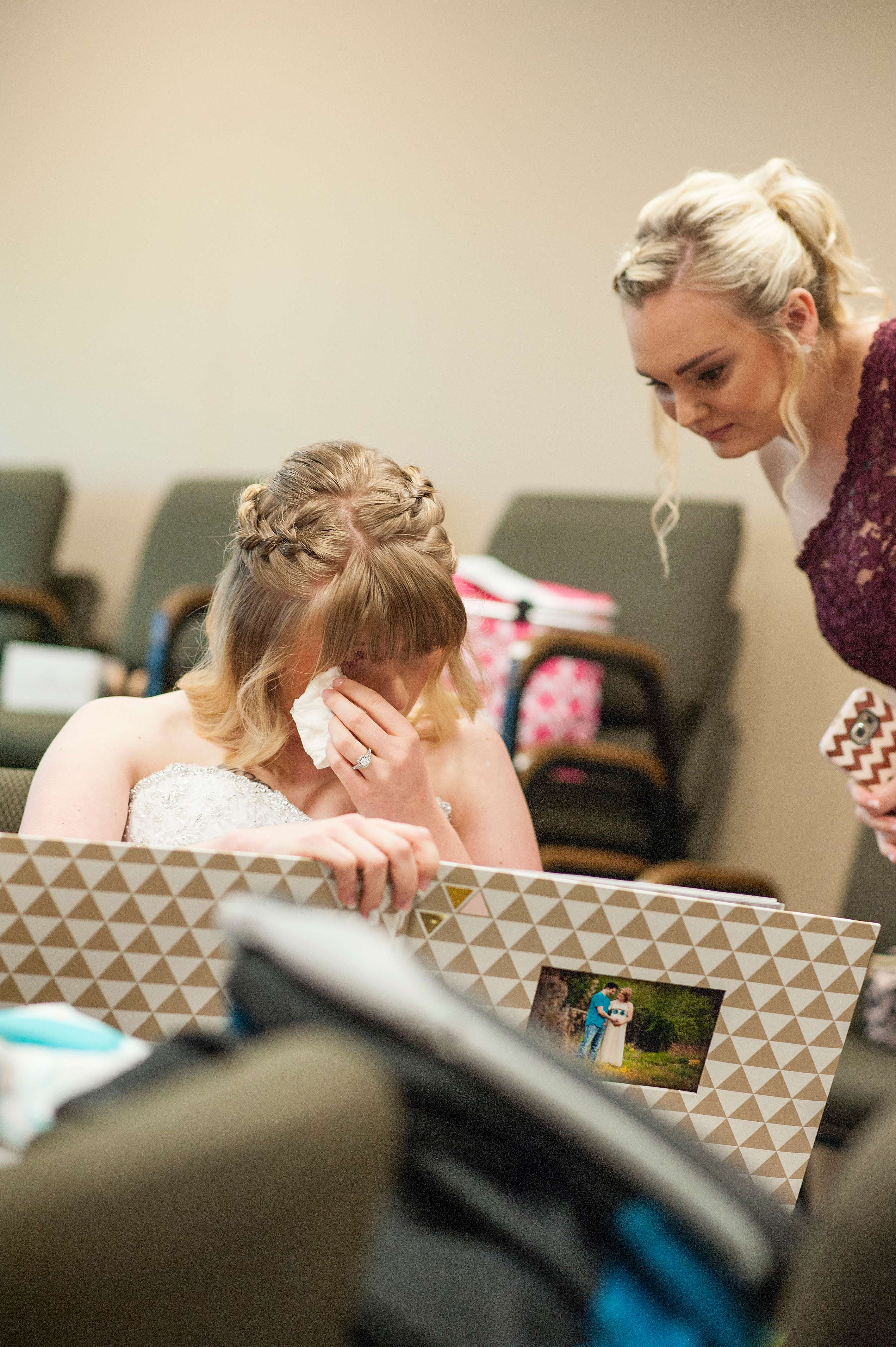 Bride crying with her bridesmaids looking at photos.