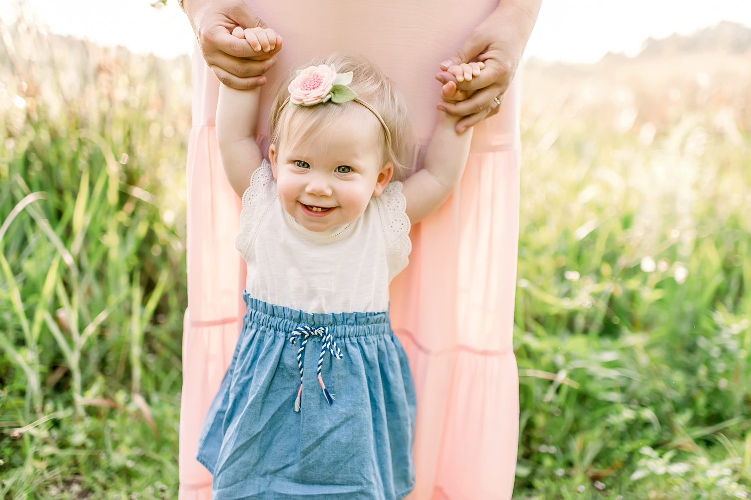 smiling one year-old walking while holding mom's hands, felt flower headband, Rya Duncklee