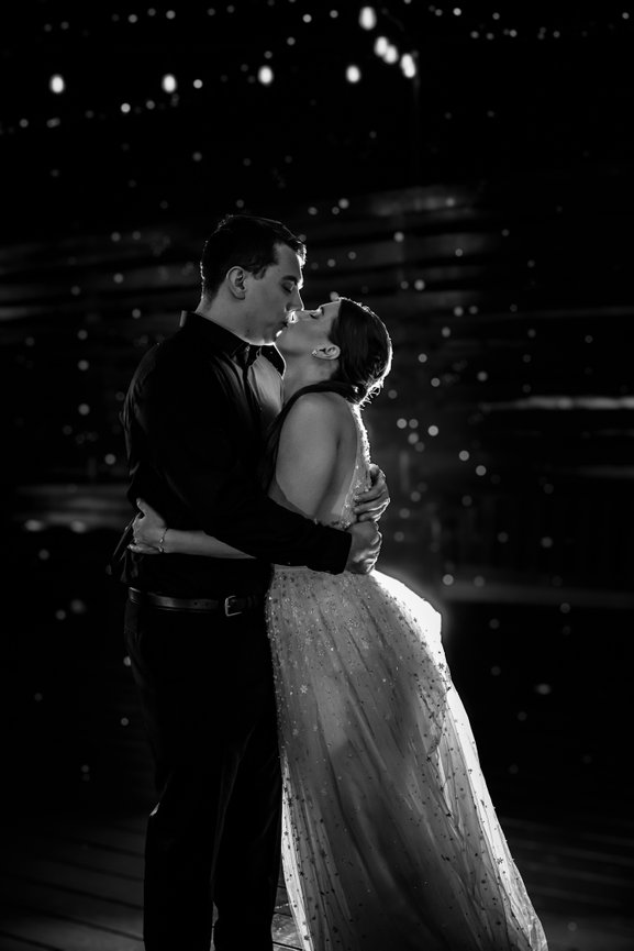 Black and white couple kissing and embracing at a formal event with dramatic lighting