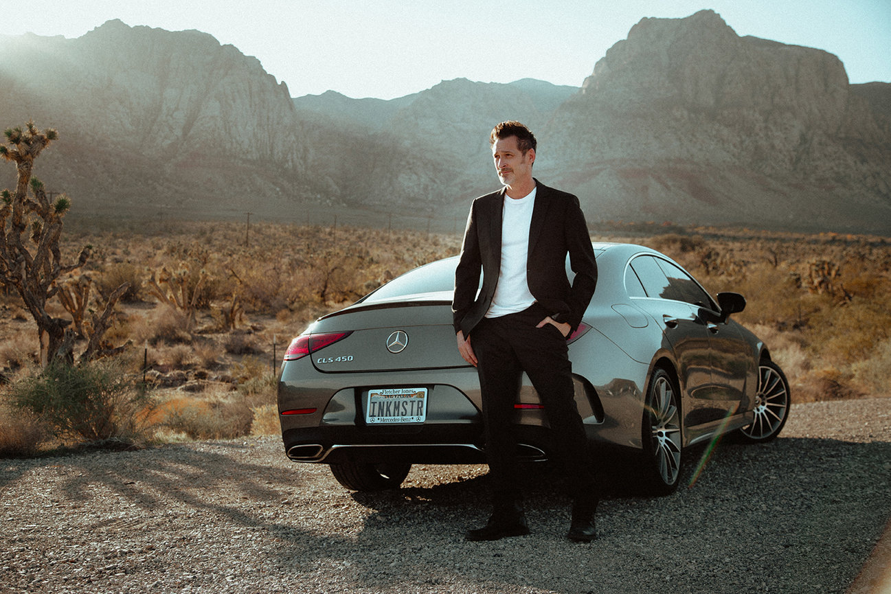 Classy and strong portrait of Joey Hamilton with his Mercedes out by Red Rock Canyon in black sport coat and pants.