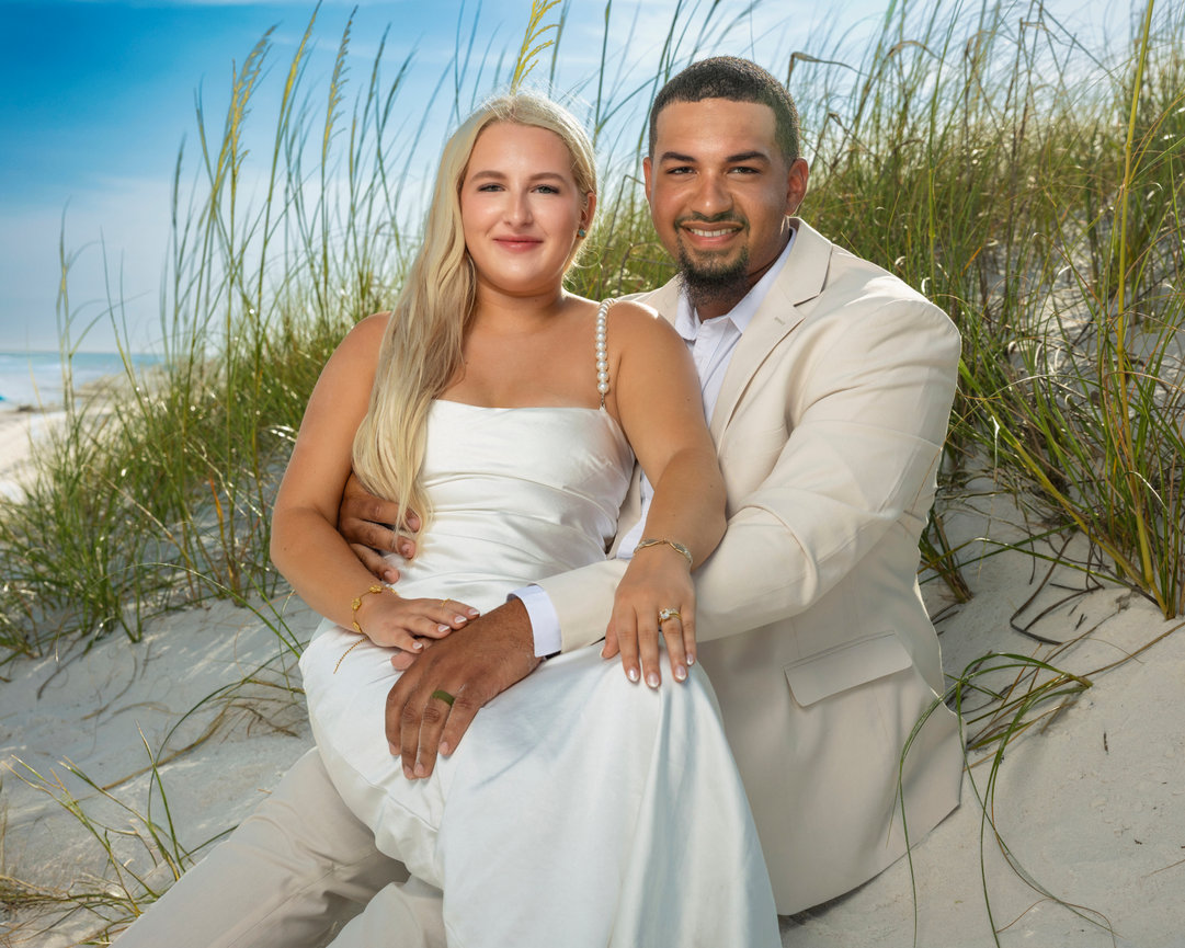Bride and groom sitting together on white sand dunes during their Alabama Gulf Coast beach wedding, captured by Dixon Creative Images