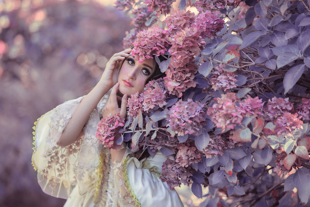 Woman with flowers in her hair leaning against hydrangeas