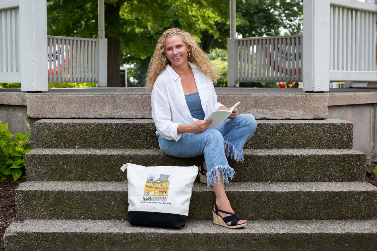 Woman sitting with a tote bag and book