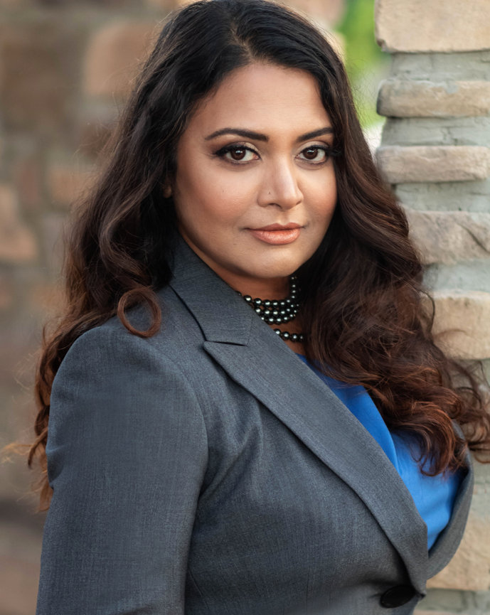Female attorney in black blazer outdoors, turned slightly away from camera.