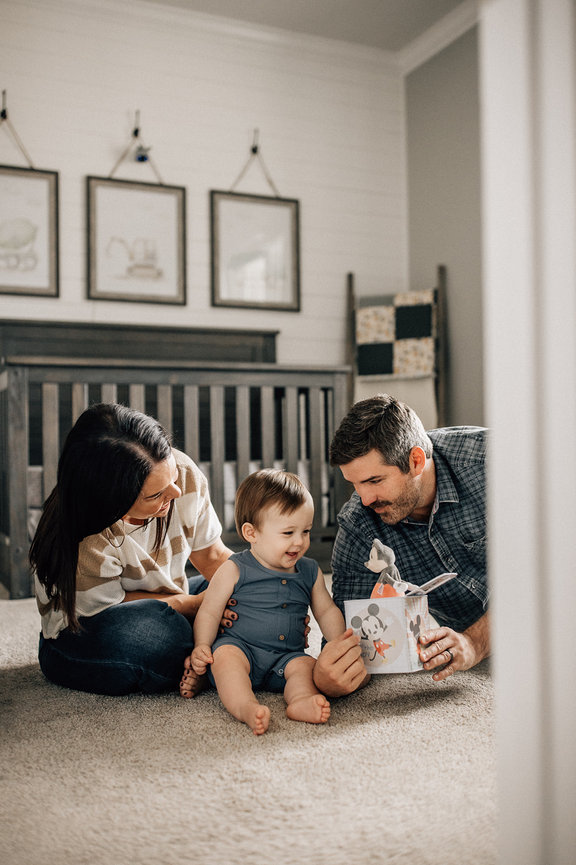 Through a door a laughing baby sits between his parents during a Huntsville, Alabama family photoshoot.