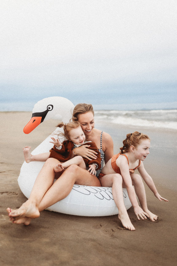 A mother and her two daughters in a tube on a New Jersey beach captured by family photographer Love of James Photography.