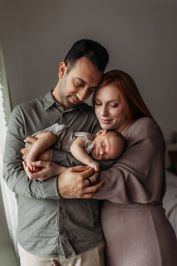 A mother and father cradle their newborn son in their arms during a studio New Jersey Newborn Photo session.