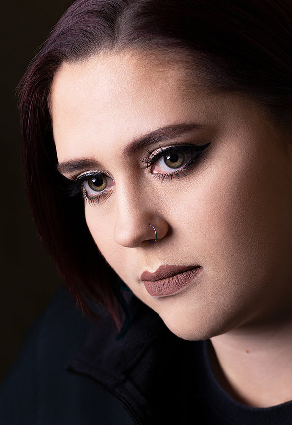 Close-up indoor portrait of a young woman with soft studio lighting, detailed eye makeup and natural expression, capturing a quiet, introspective mood with a refined fine art feel.
