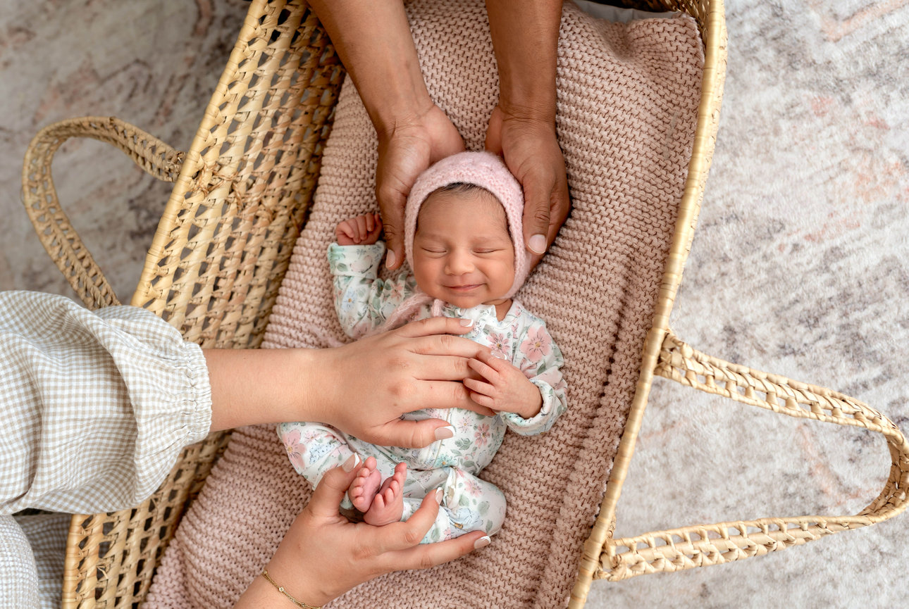 Sleeping newborn wrapped in pink blanket in a woven basket with lace bonnet- San Diego Photography