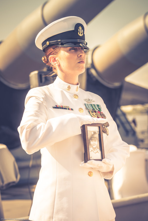 Navy Chief holding a framed picture of a POW during a ceremony onboard the USS NEW JERSEY