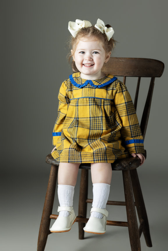 Girl in yellow checkered dress on a chair