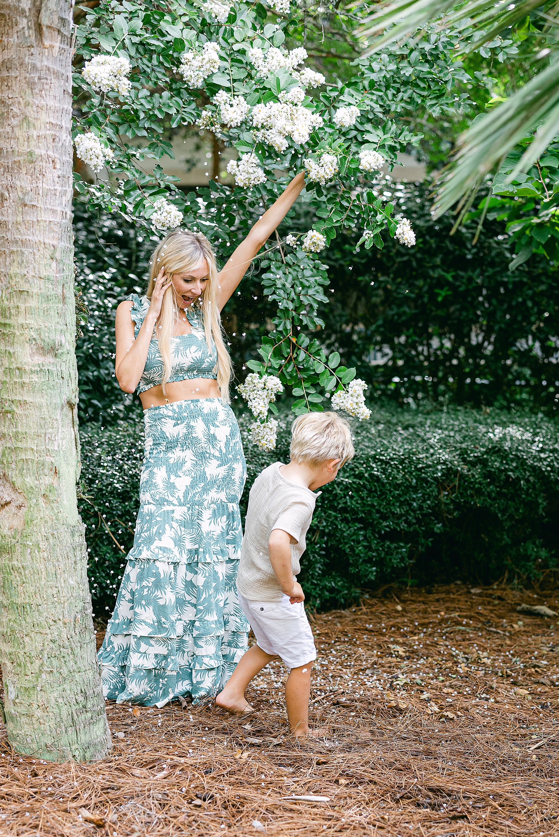 woman standing under falling white flowers with little boy