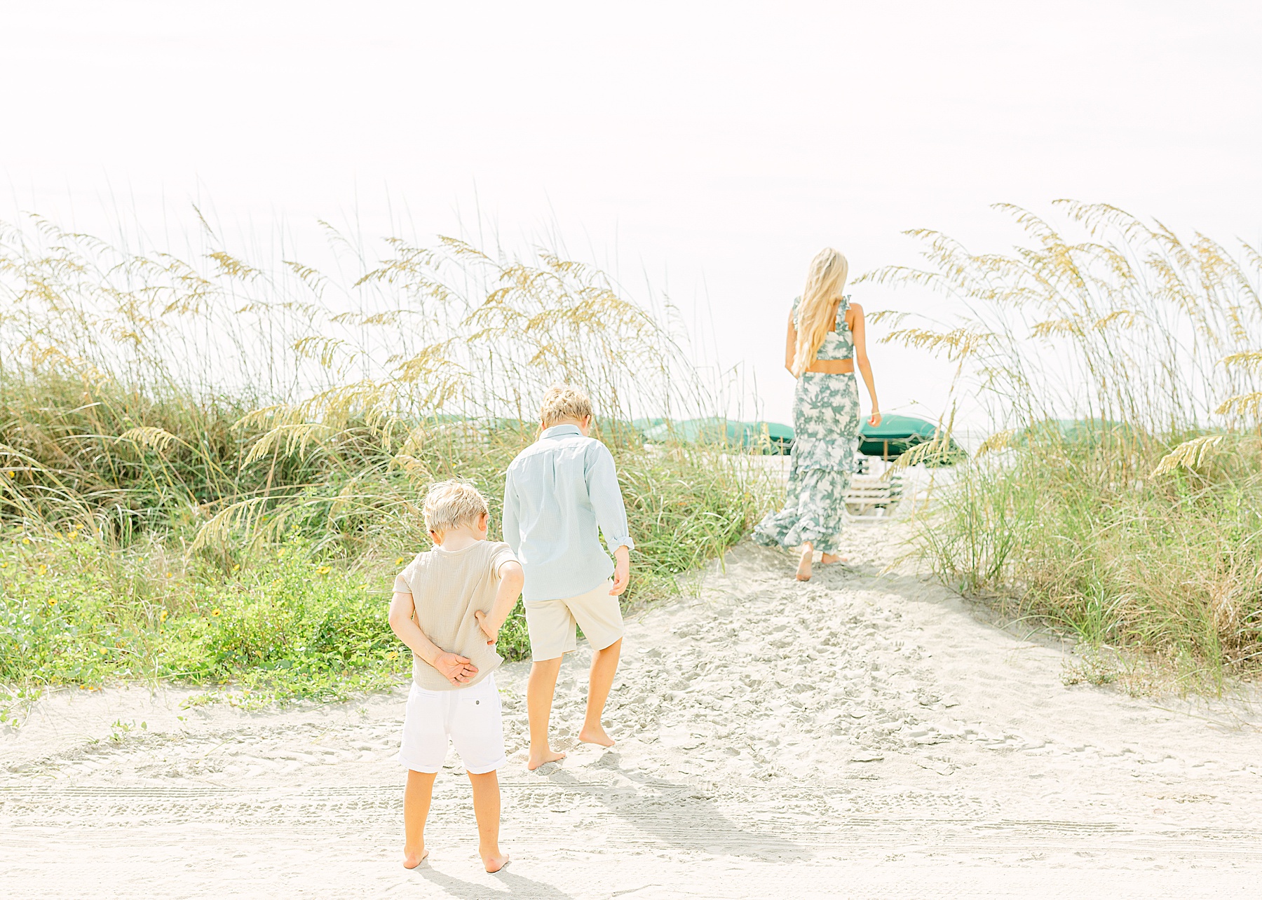 family walking toward the ocean wearing neutral colors
