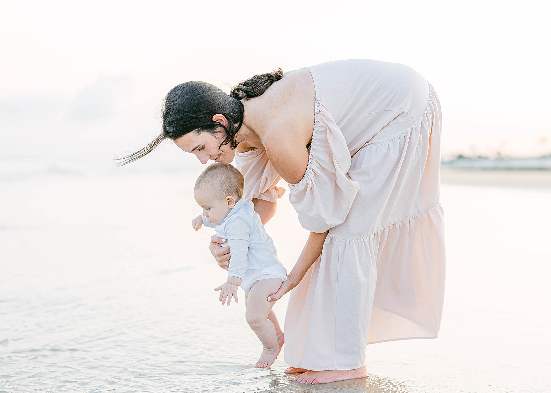 woman holding baby boy at sunset on the beach