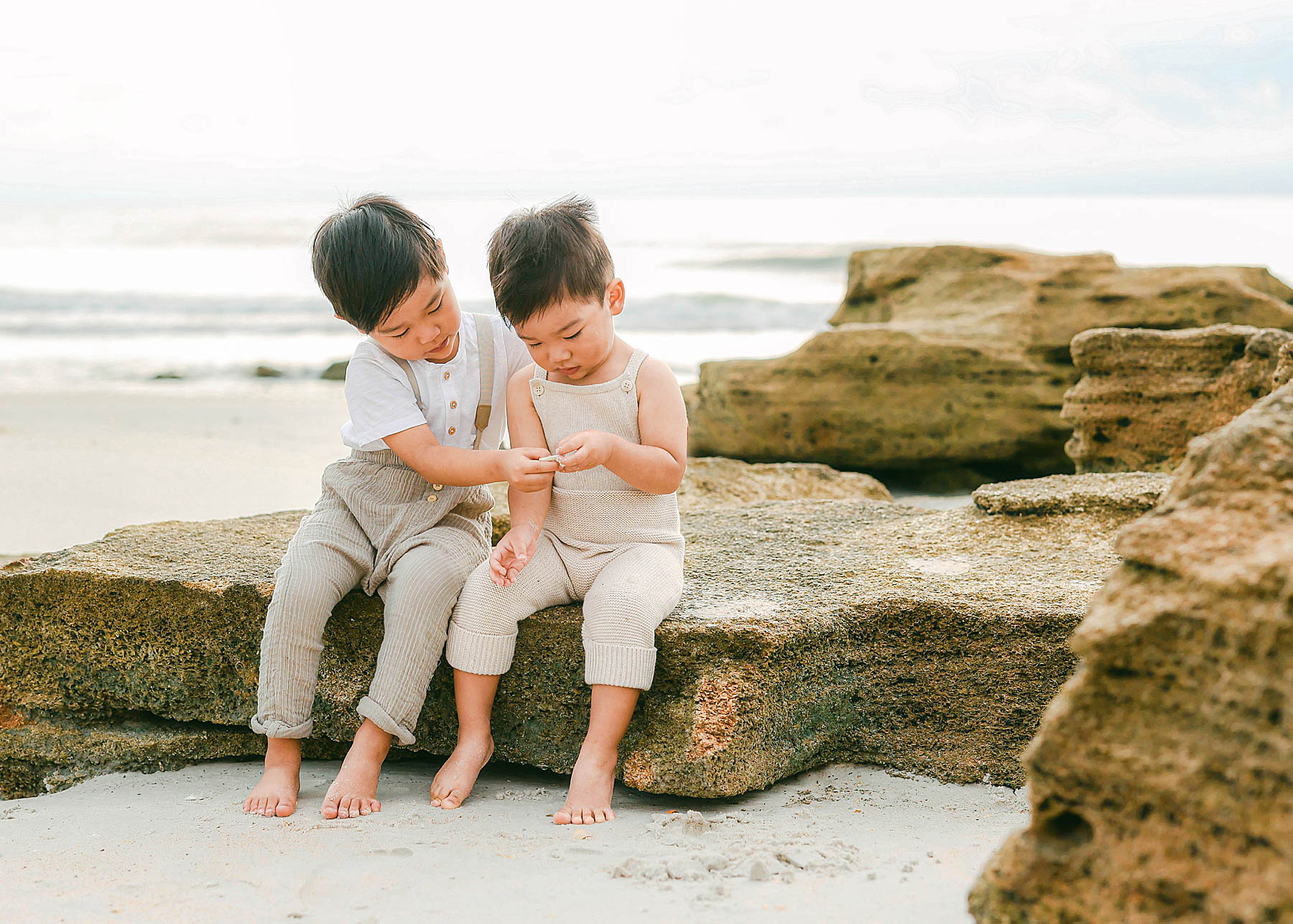 little boys sitting on rocks at beach