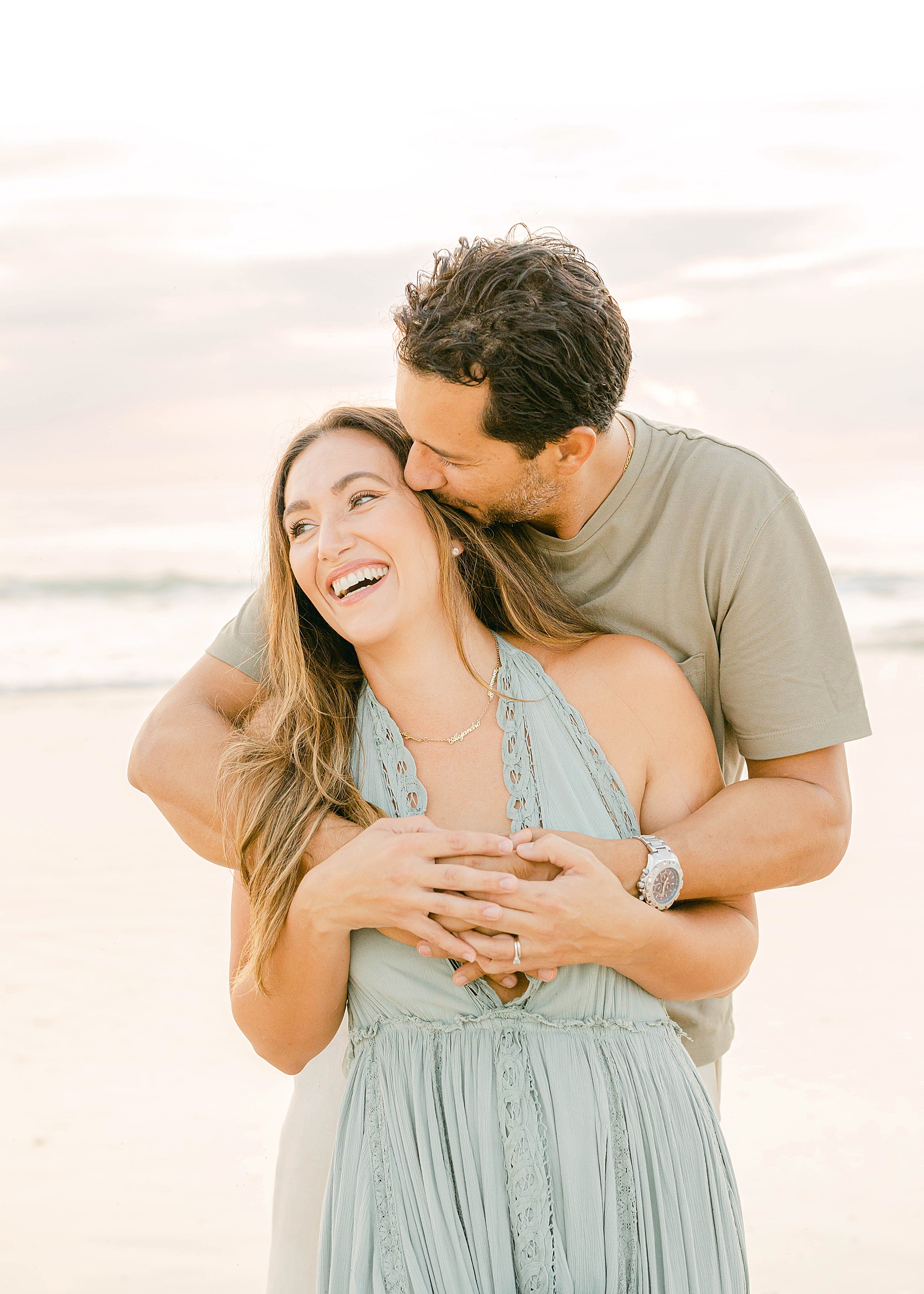 man kissing woman in green dress on the beach