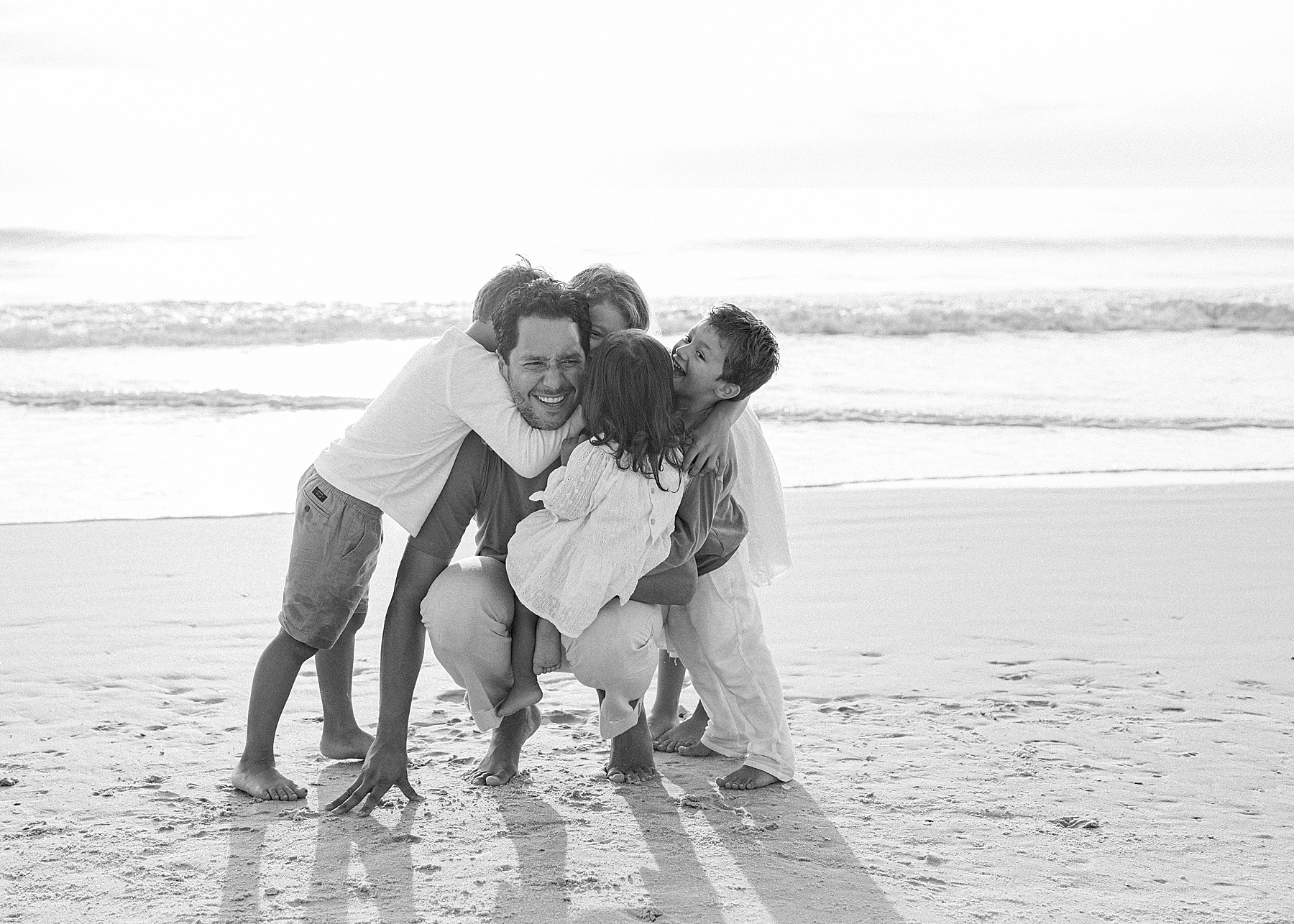 man holding children laughing on the beach