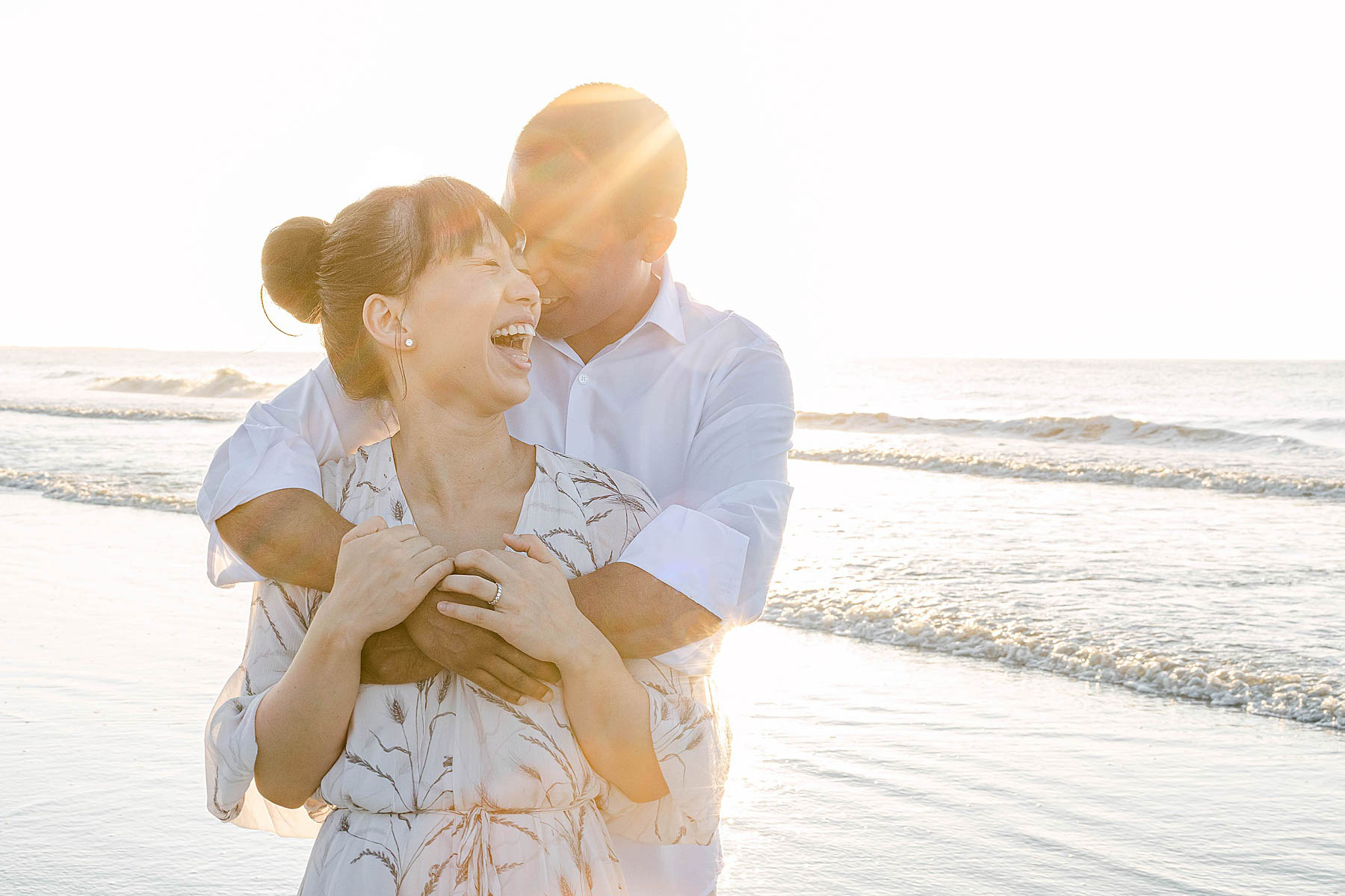 woman and man embracing at sunrise on the beach and laughing