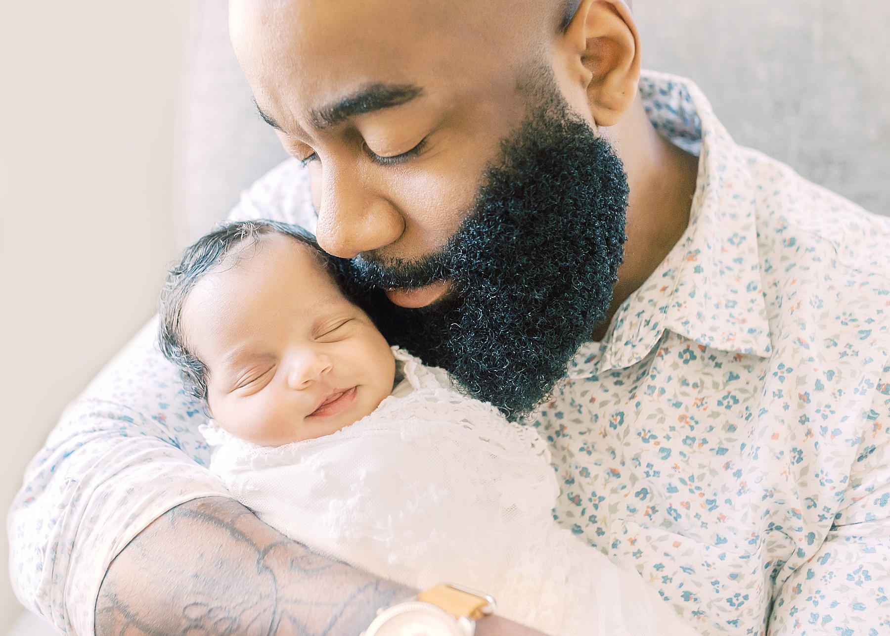 black man holding a newborn baby girl smiling