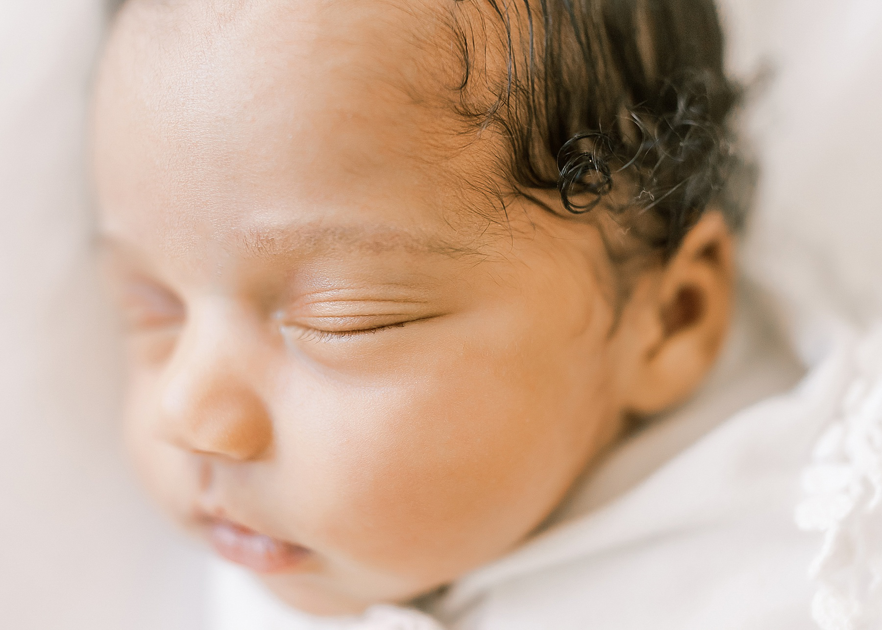 newborn baby girl close up of face with curly black hair