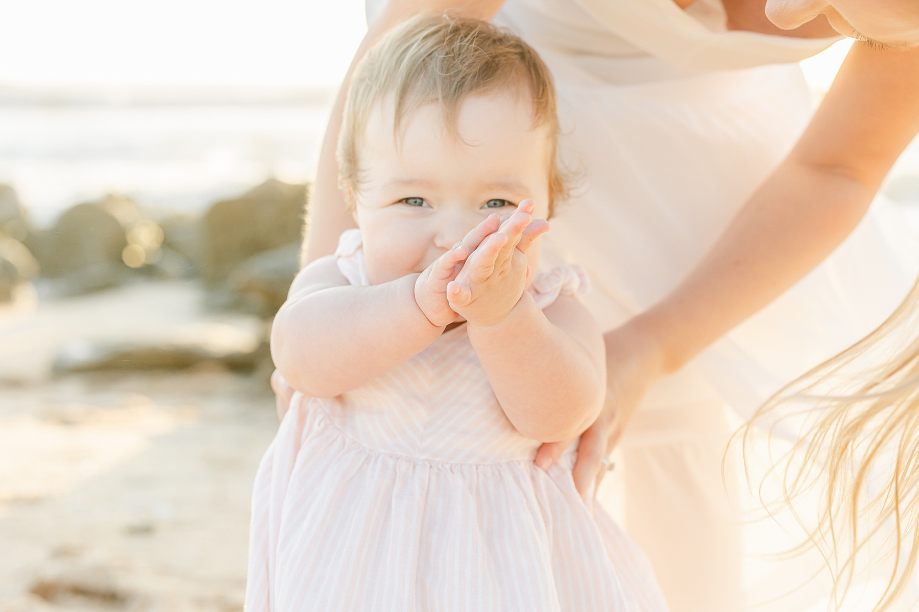 baby girl smiling with hand in front of face chubby arms pink white stripe dress