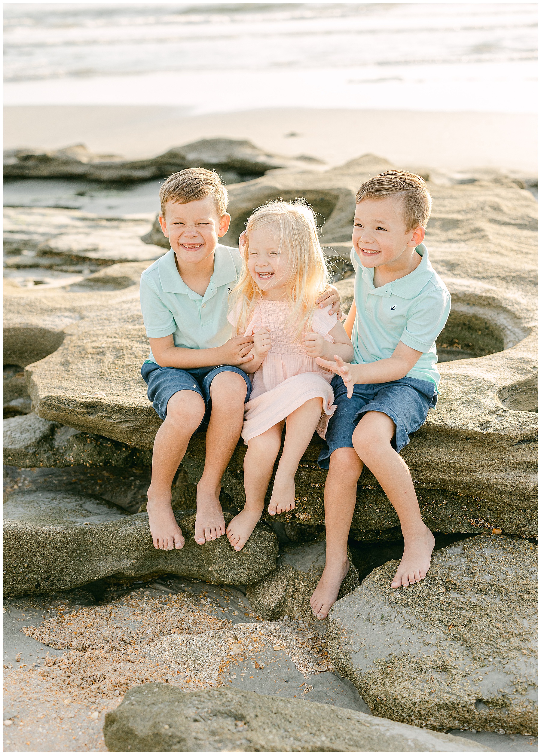 three children sitting on the rocks on the beach in saint augustine florida