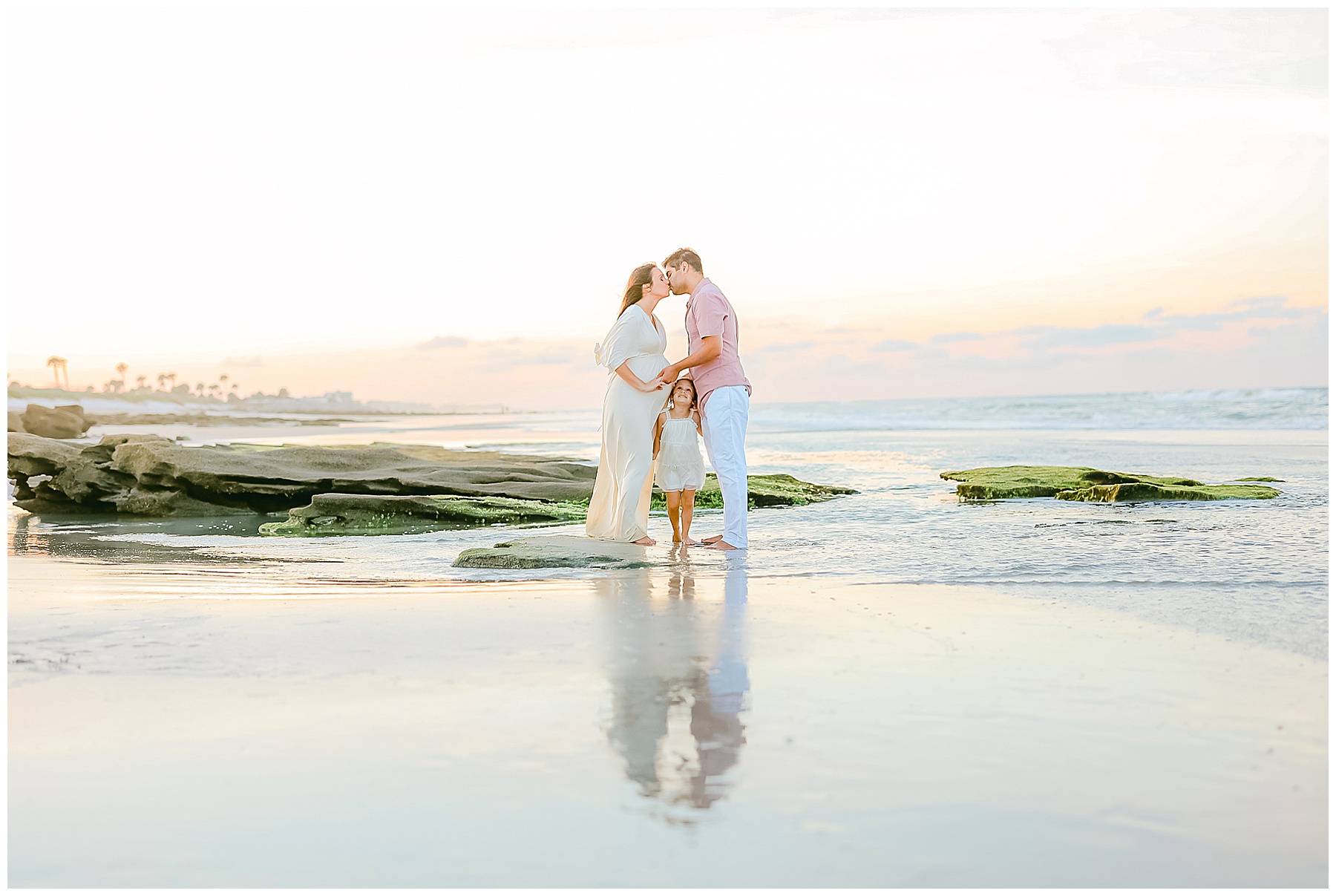 family standing on the beach in the water at sunset in saint augustine florida