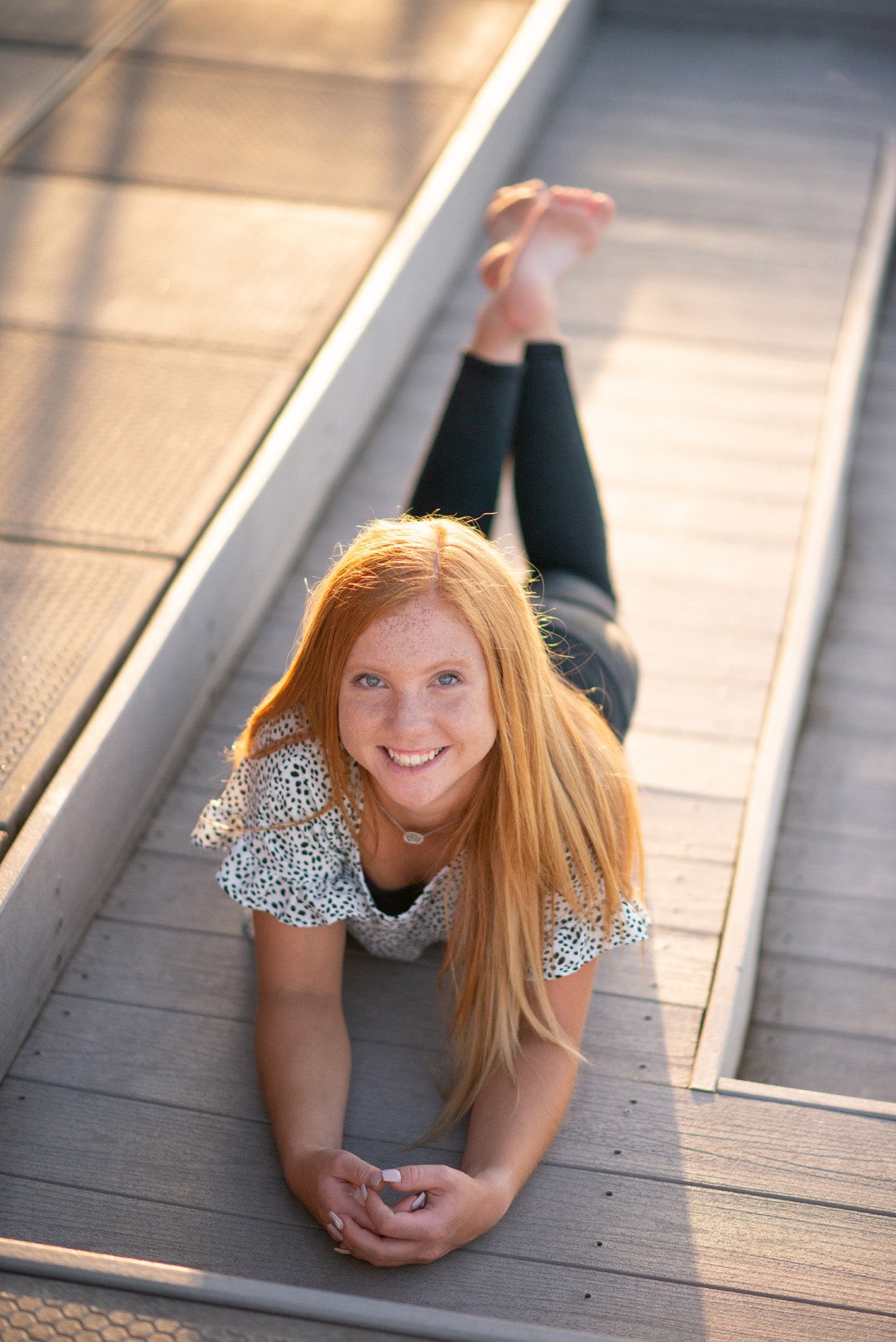 Senior girl in print top laying on a Tablerock Lake dock.