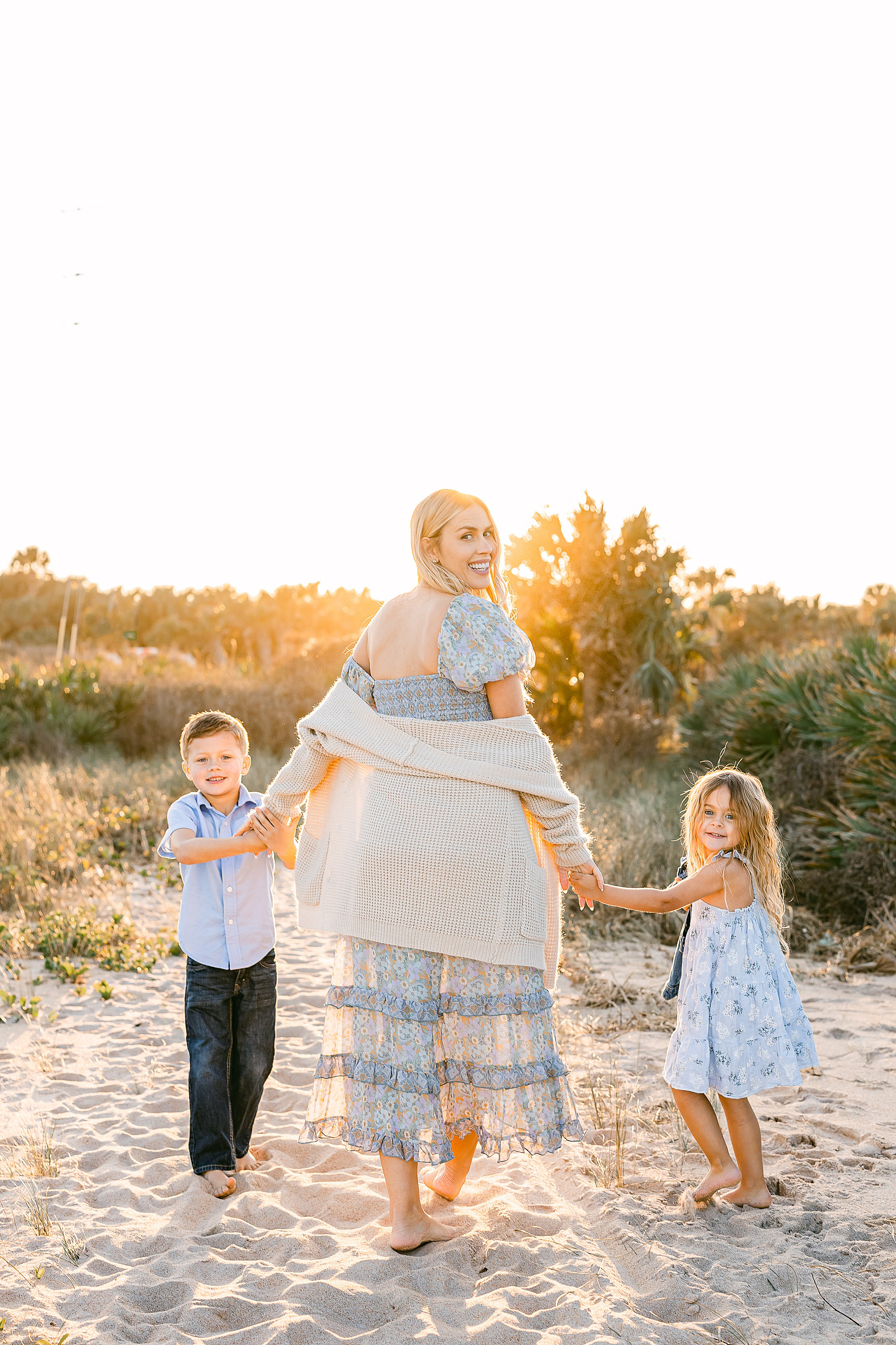 blond woman walking on the sand with two children in coordinating clothing