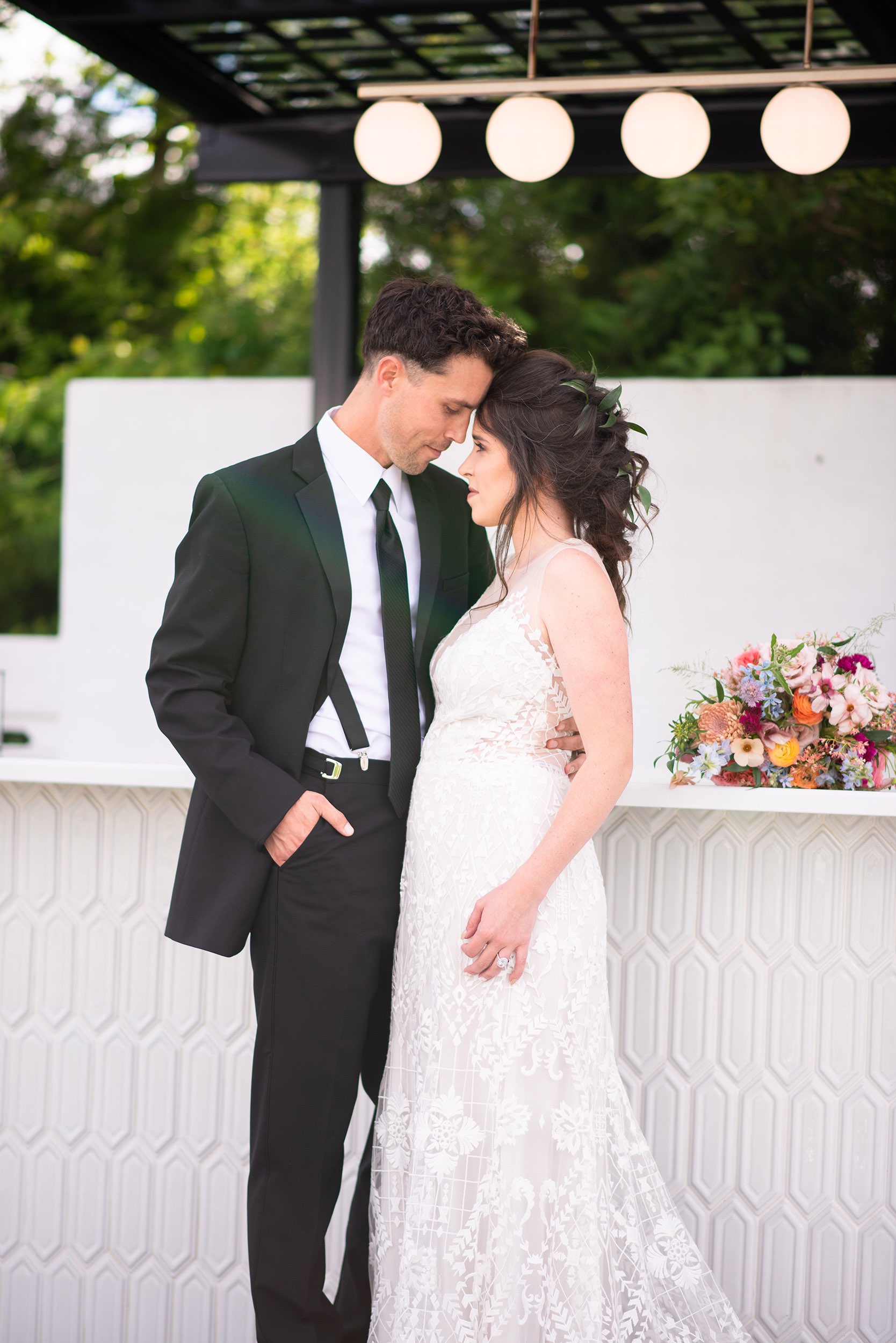 Bride in boho gown and groom in black suit with black tie.