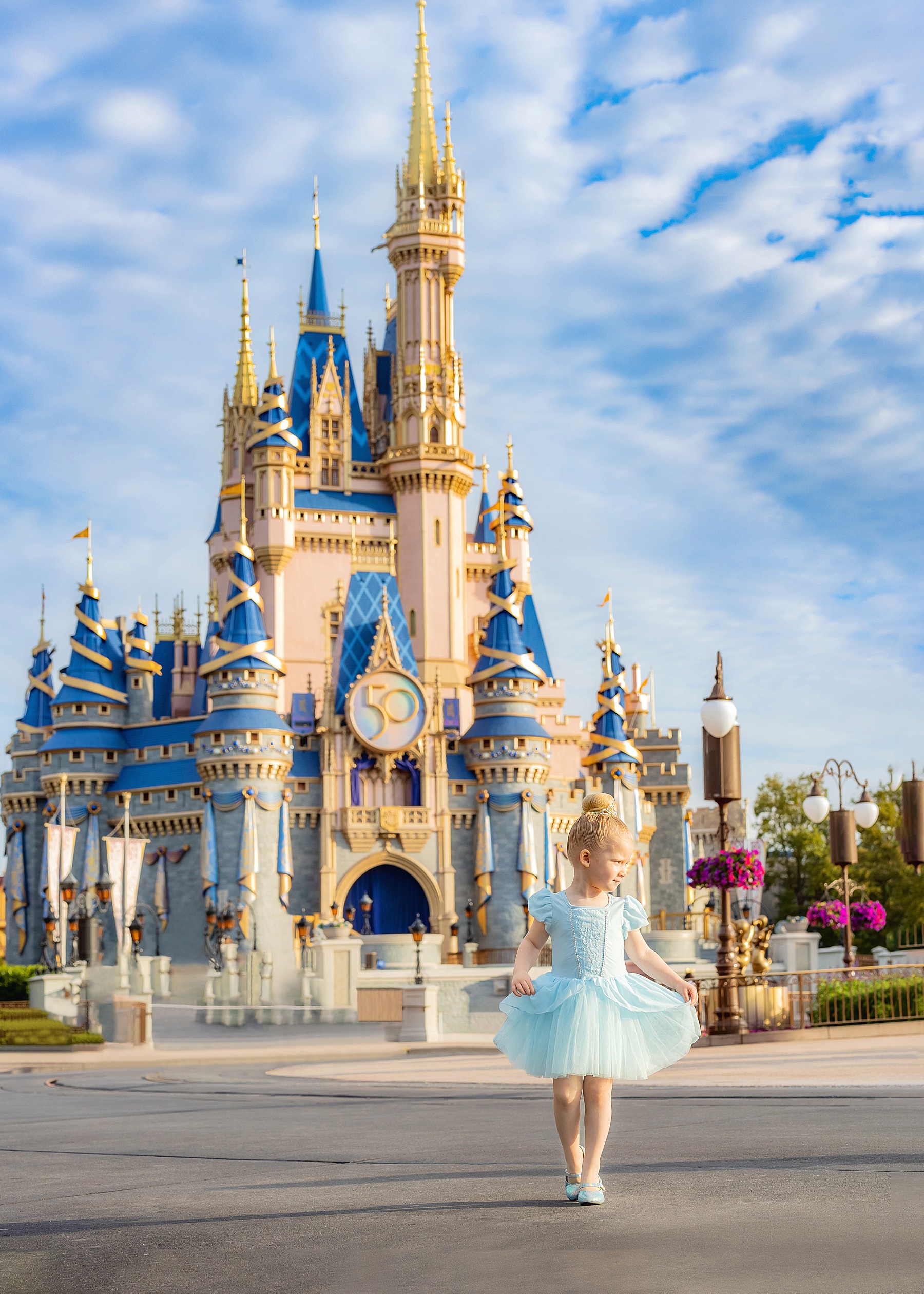 little girl in blue Cinderella dress in front of Cinderella's Castle at Magic Kingdom Disney