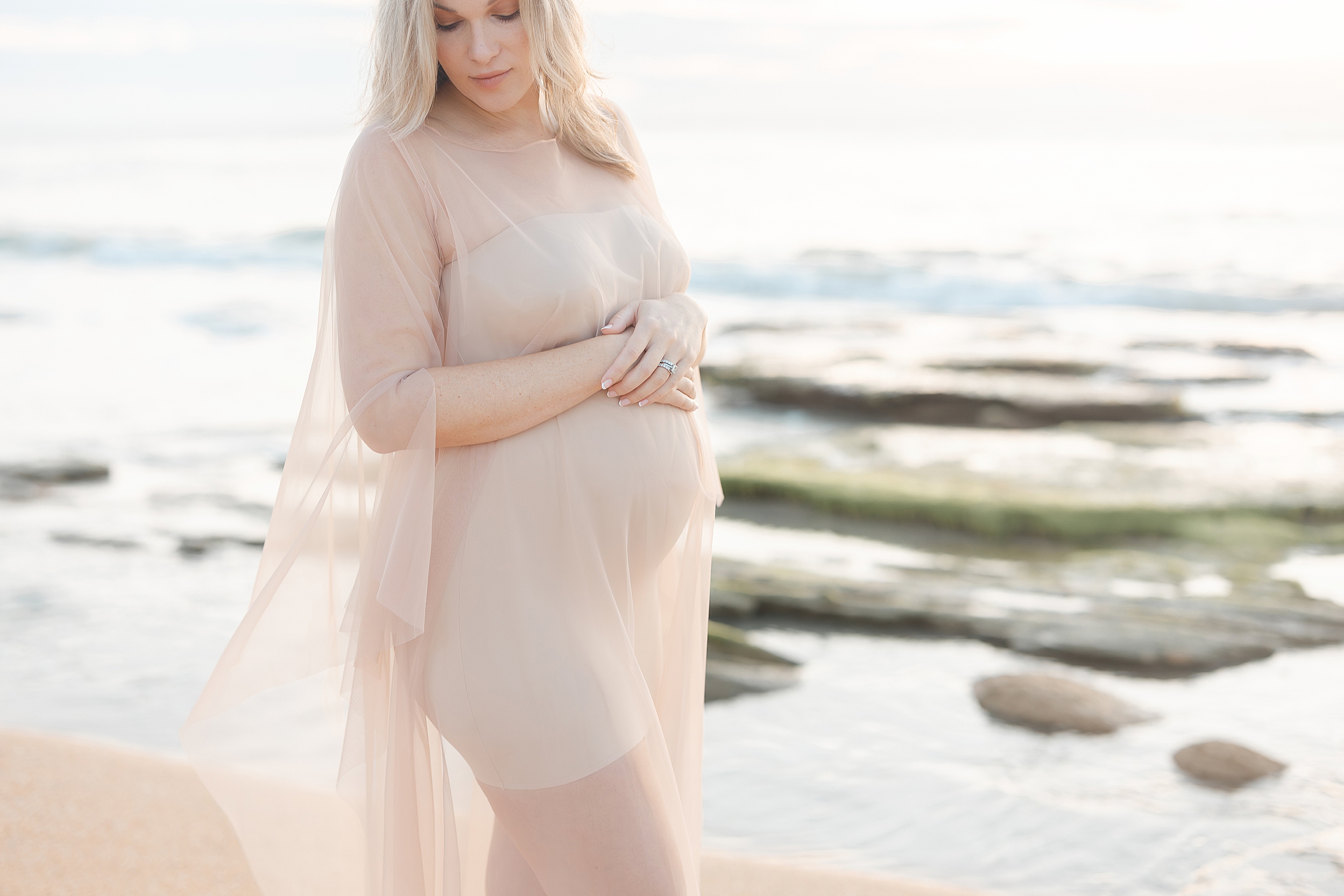 Sunrise maternity portrait in a long flowing nude tulle dress on the coast in St. Augustine.