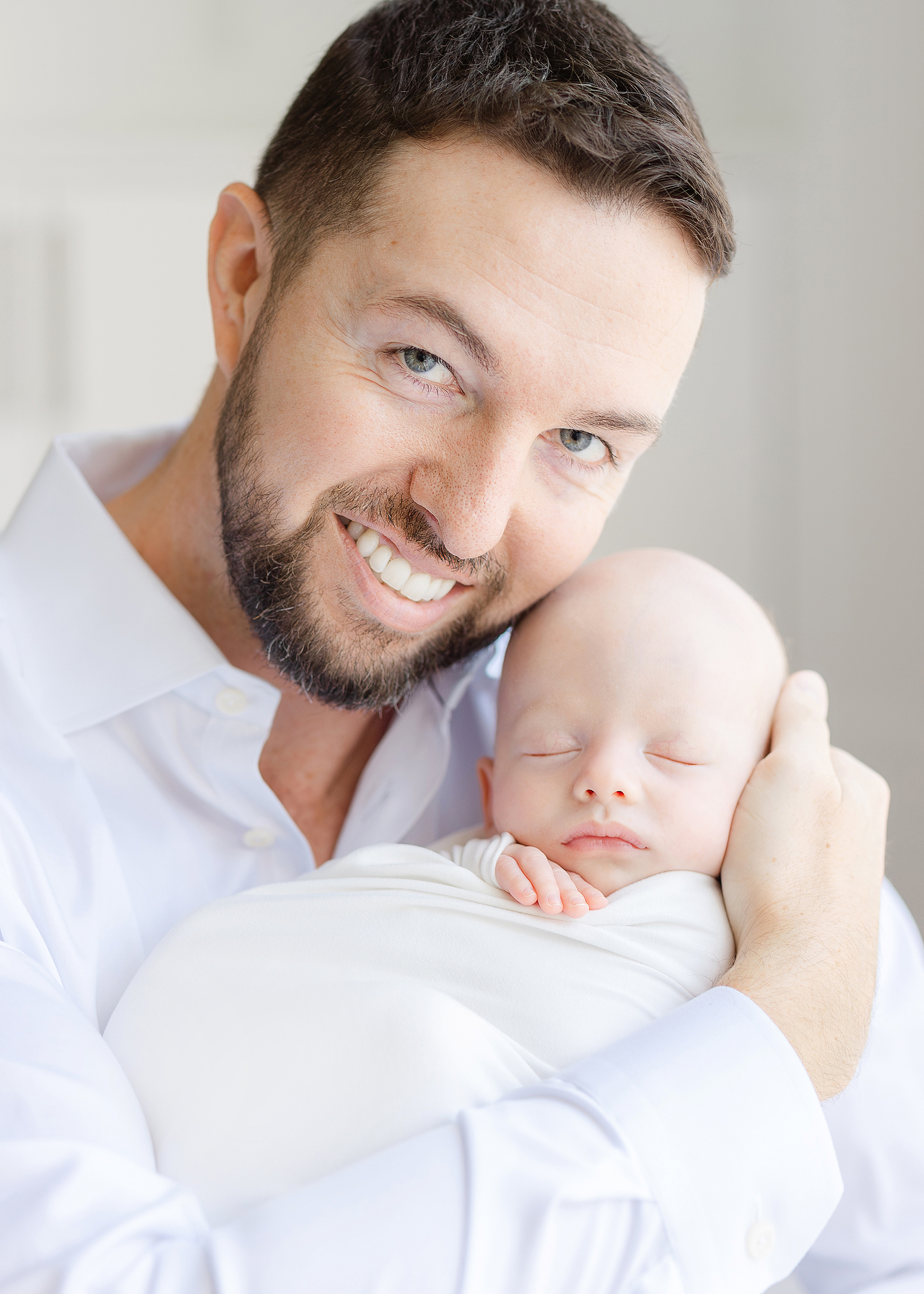 Man in white shirt holding newborn baby boy.