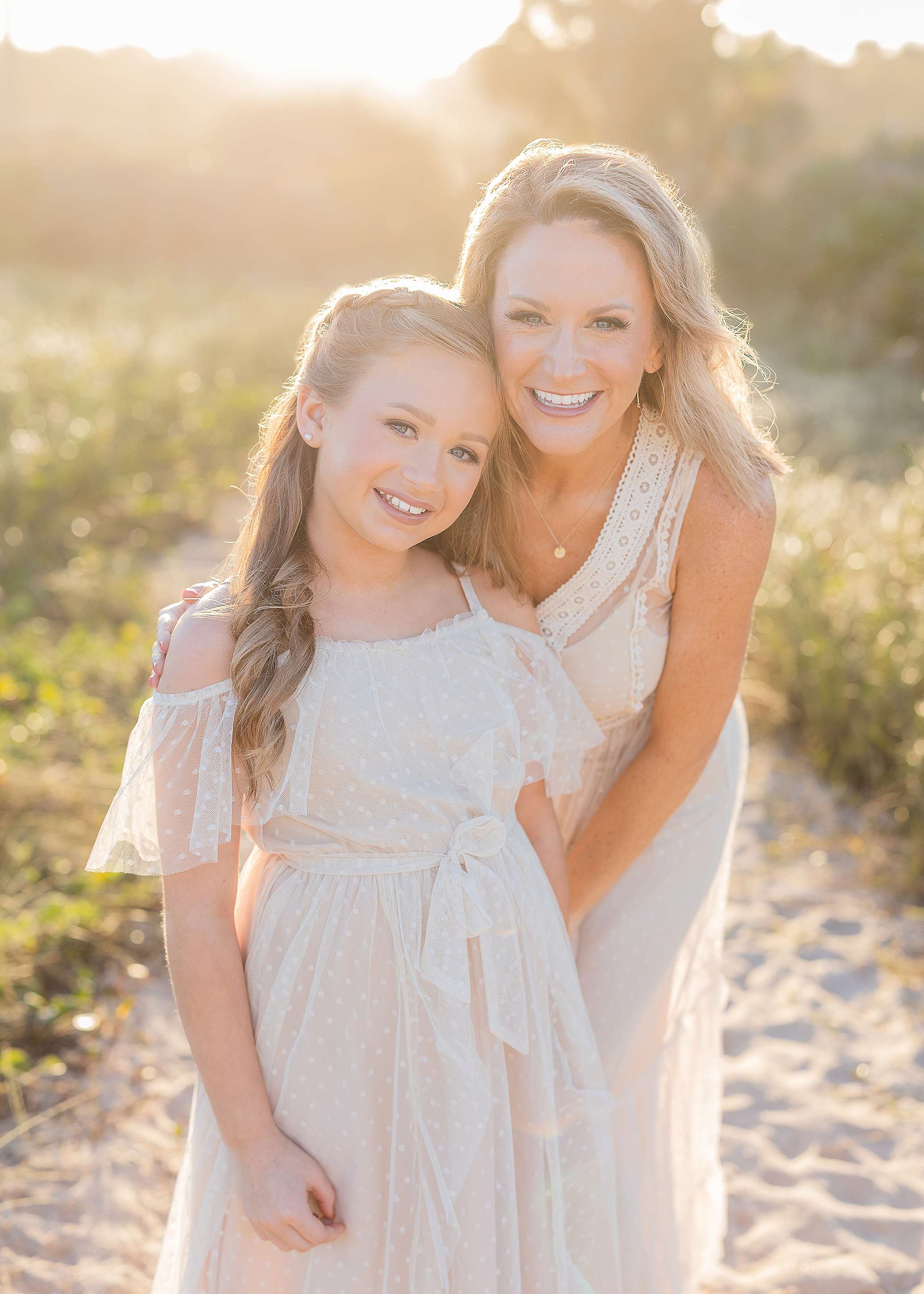 A mother and daughter pose for a photo on the beach.