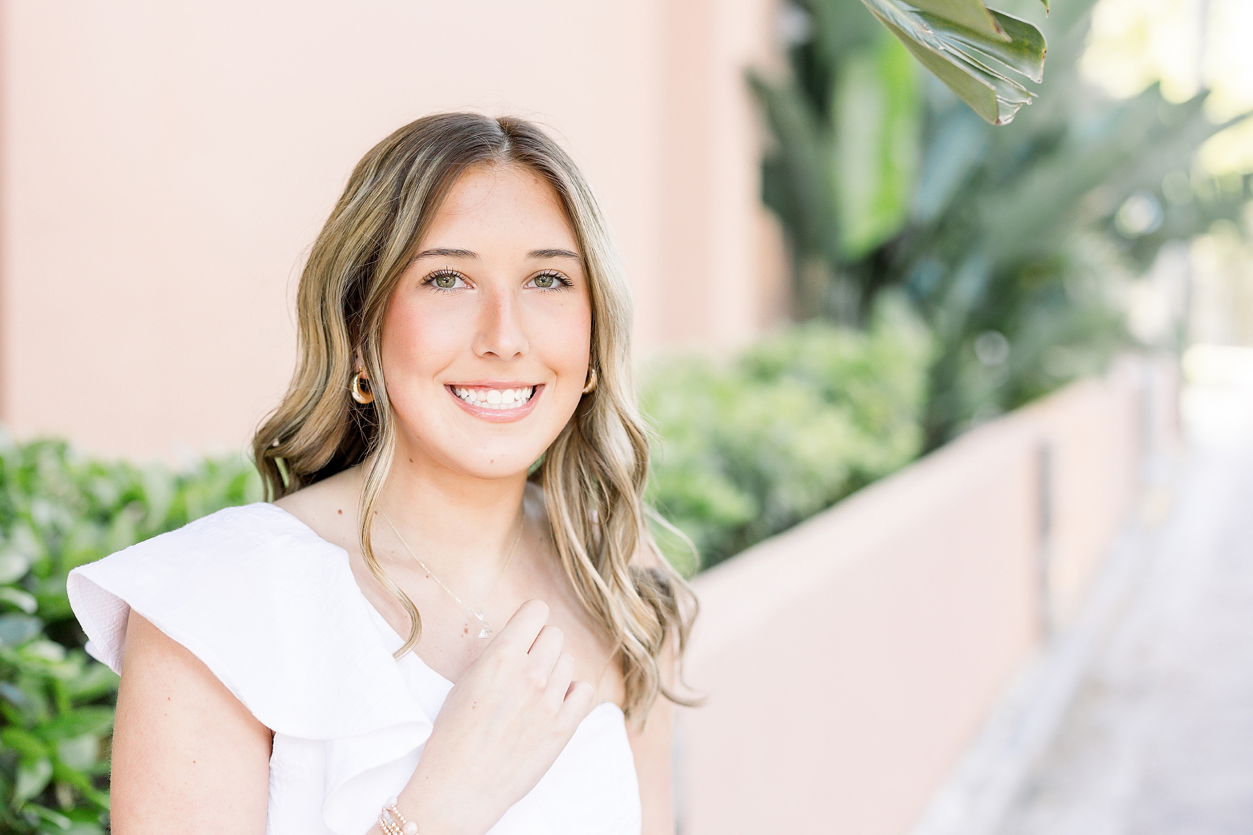 Grad portrait of a young woman standing against a pink wall in historic downtown St. Augustine.