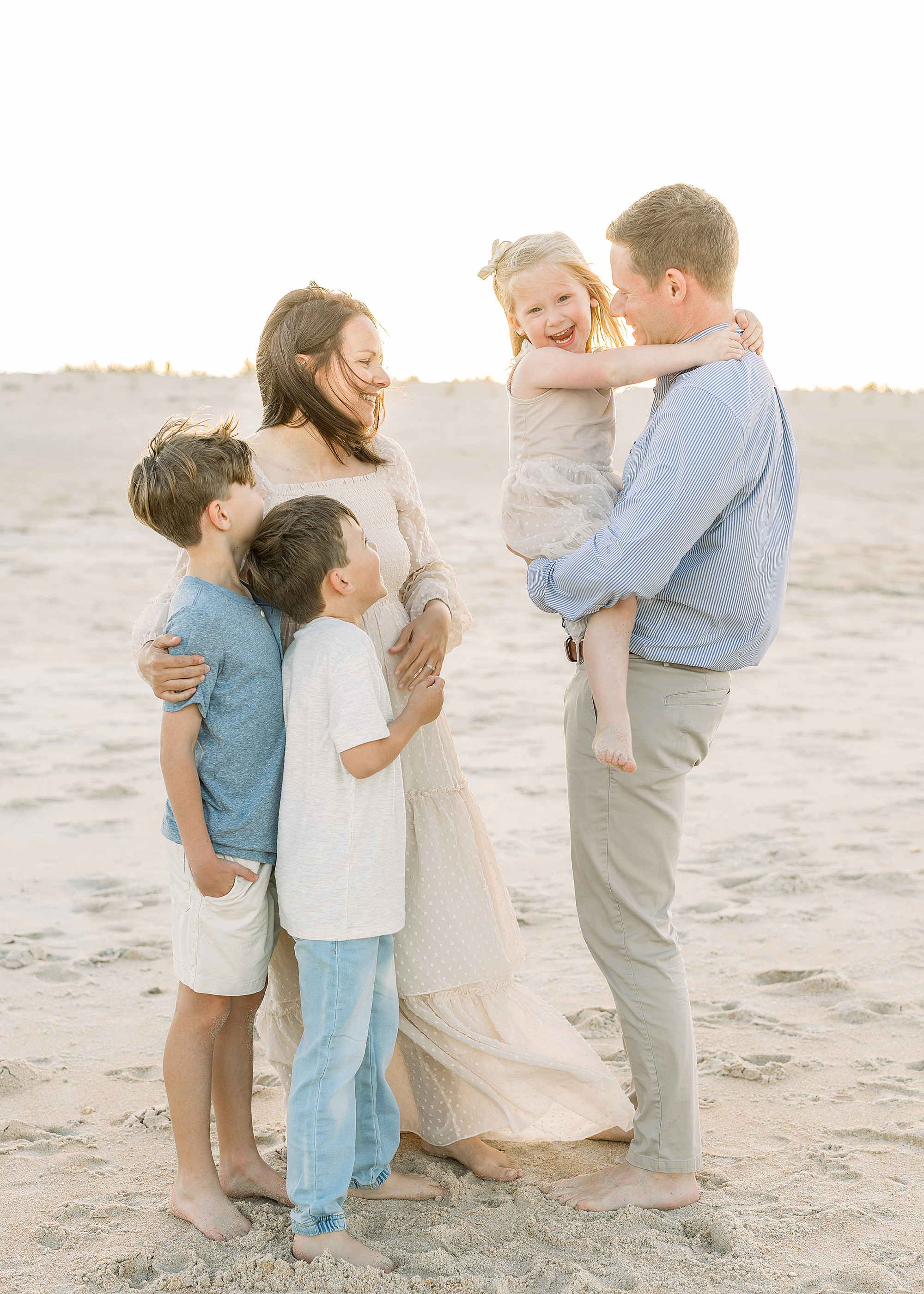 A family of five laughs together on the beach at sunset in St. Augustine.