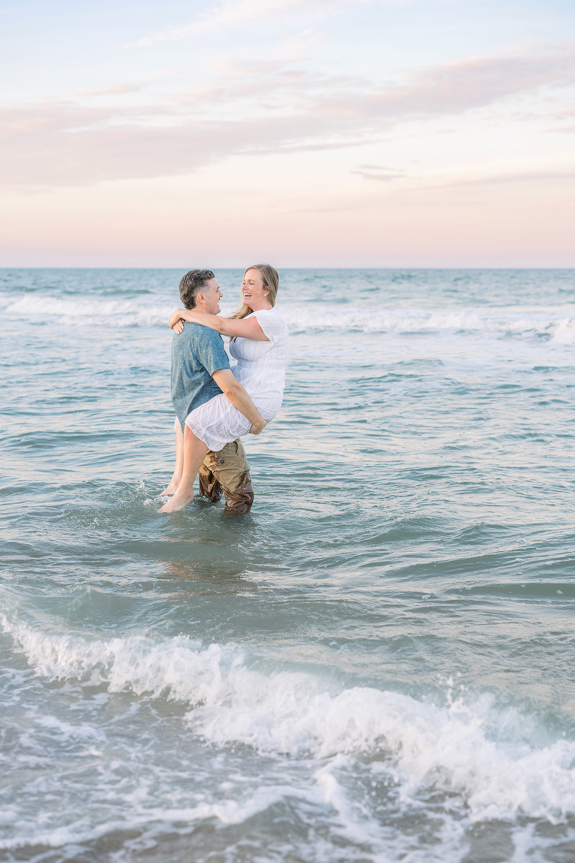 A colorful pastel sunset couples portrait in the water on St. Augustine Beach.