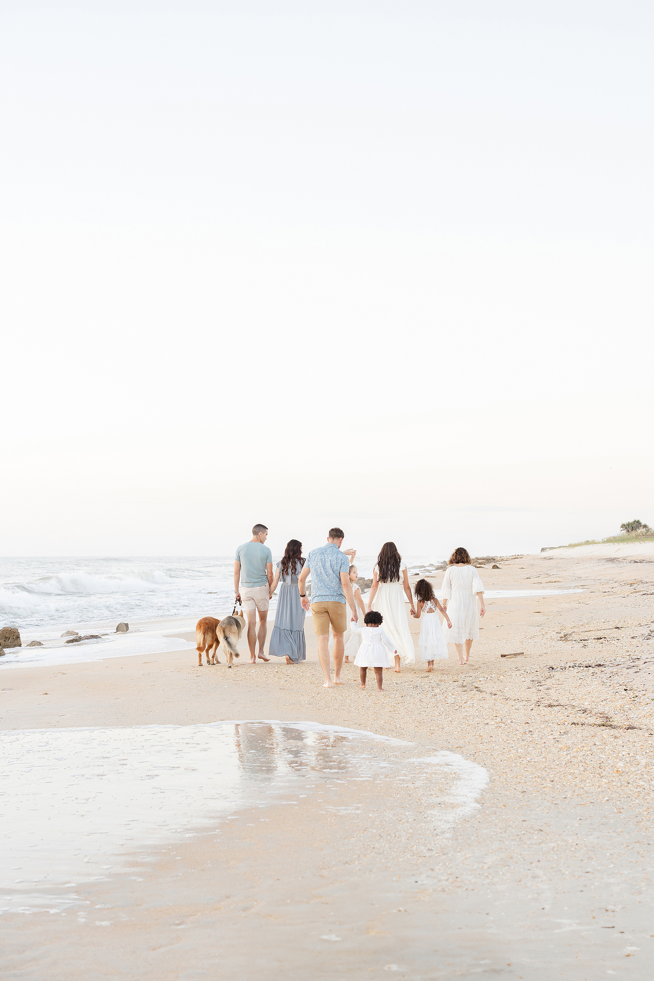 An extended family walks on Saint Augustine Beach together at sunrise.