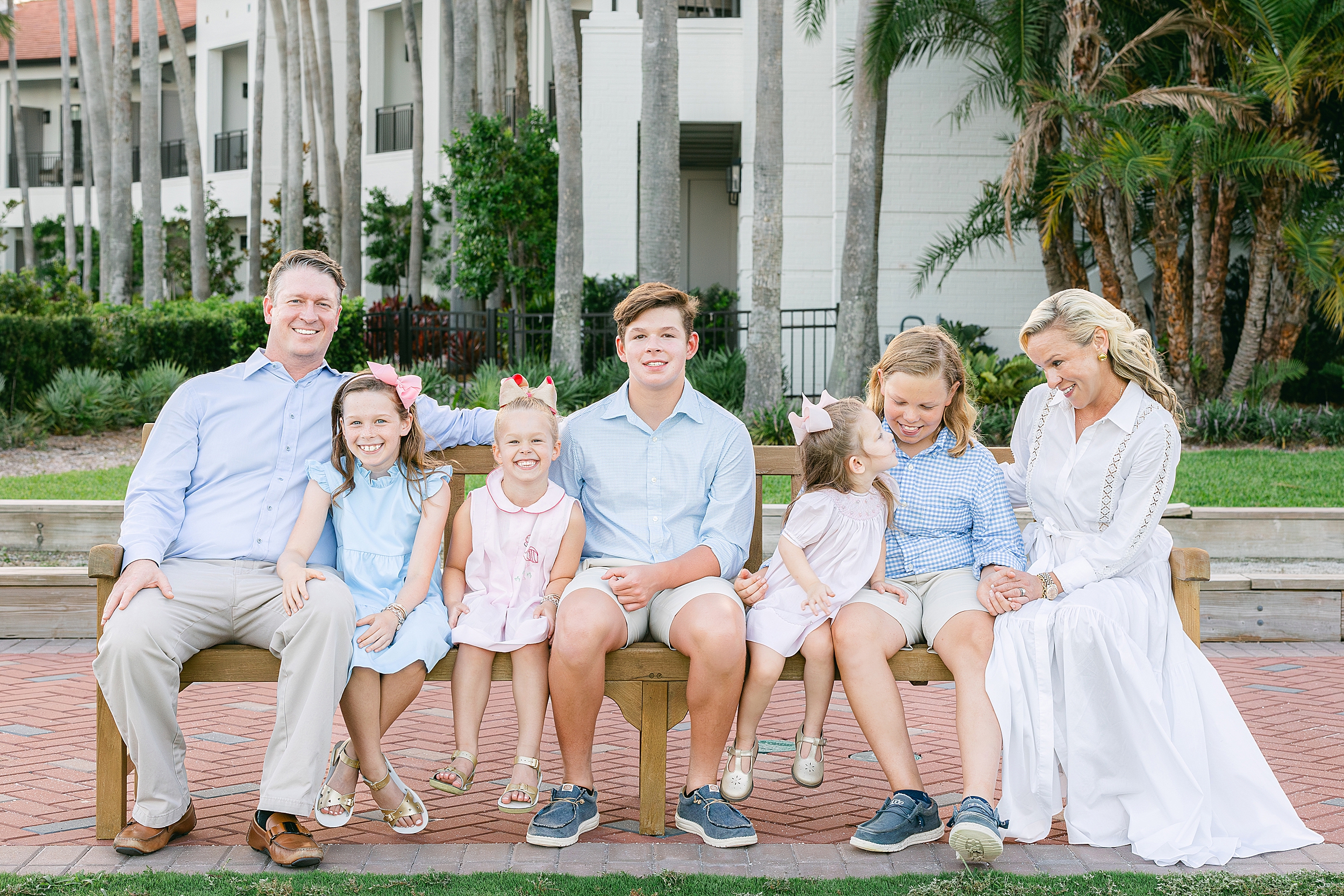 A family sits on a bench on the golf course at Ponte Vedra Inn and Club.