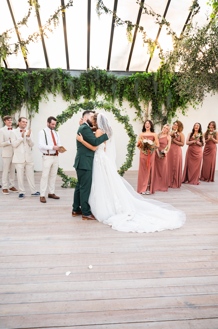 Bride and groom kissing as their wedding party celebrates.