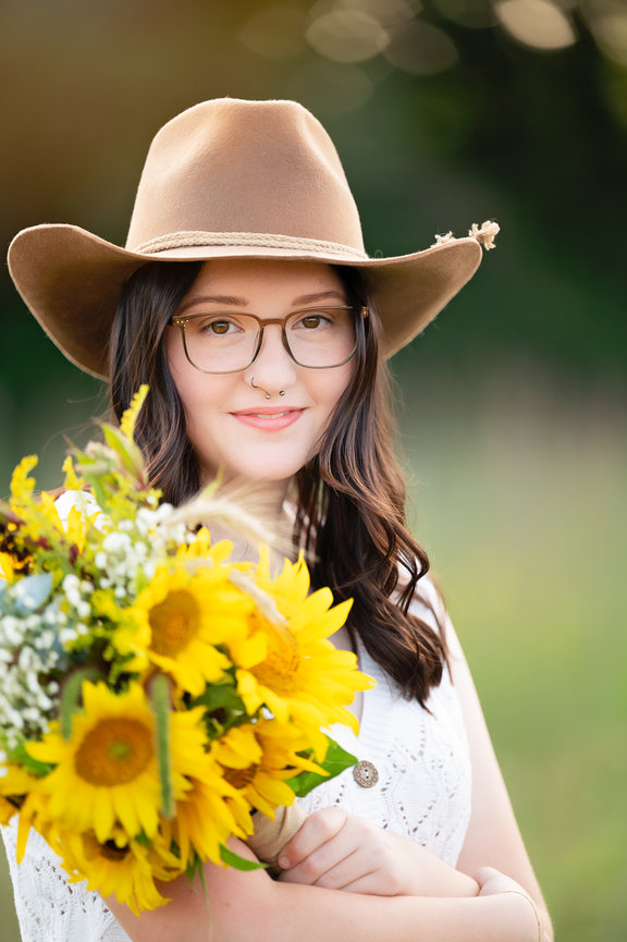 Onalaska Wisconsin Senior standing in a field with a cowboy hat and sunflowers