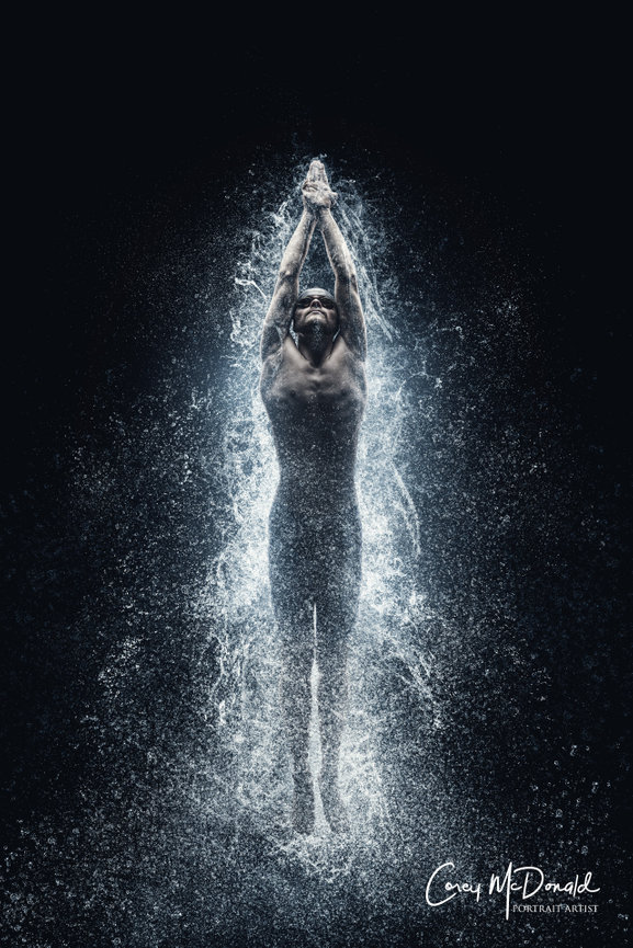 A swimmer emerging from water, droplets splashing around, creating dynamic patterns against a dark background.